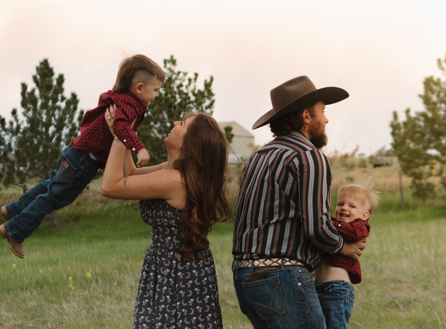A family plays and lifts children in the air during a sunset photoshoot in nature.