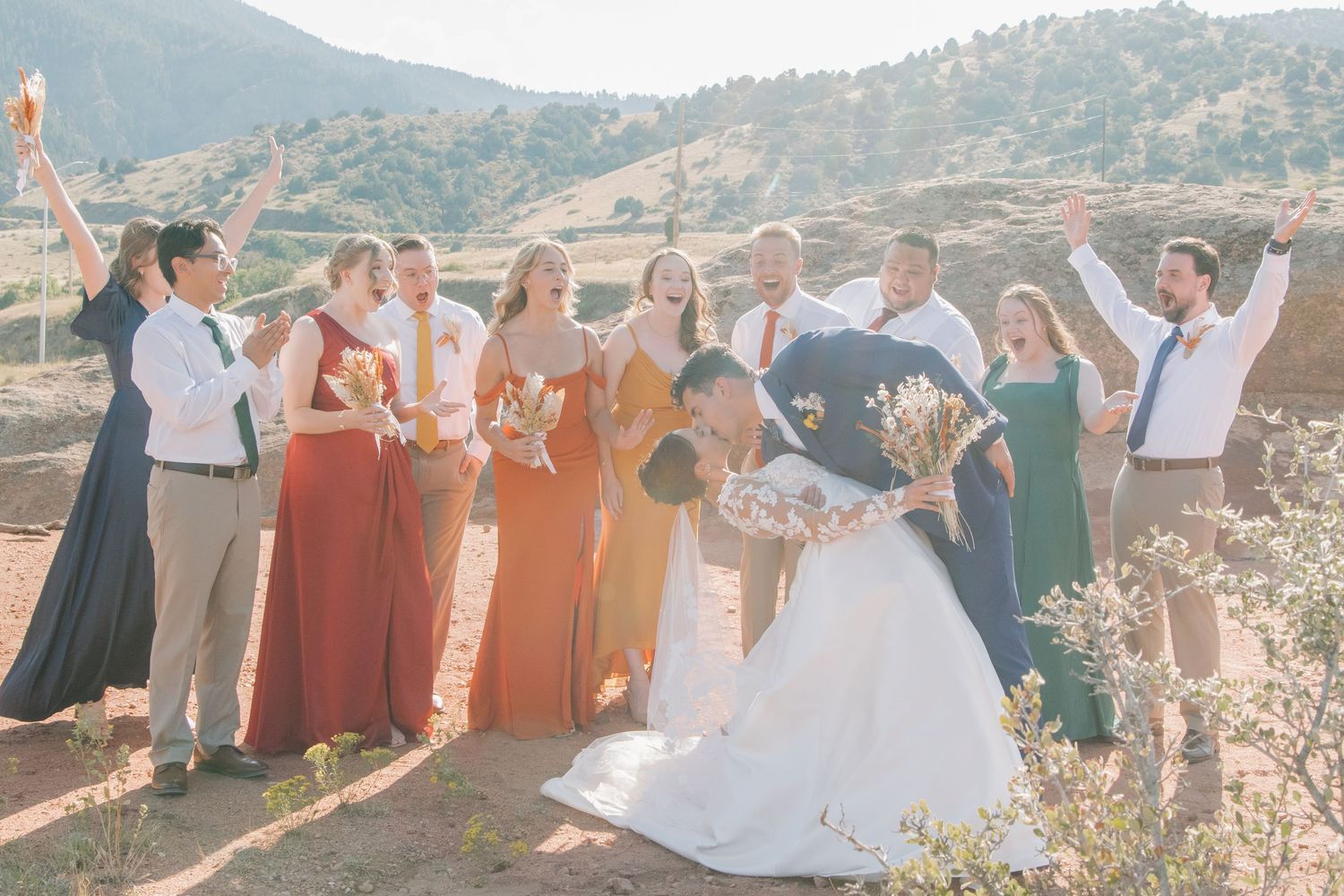 Wedding party members lined up outdoors with mountains visible in the background.