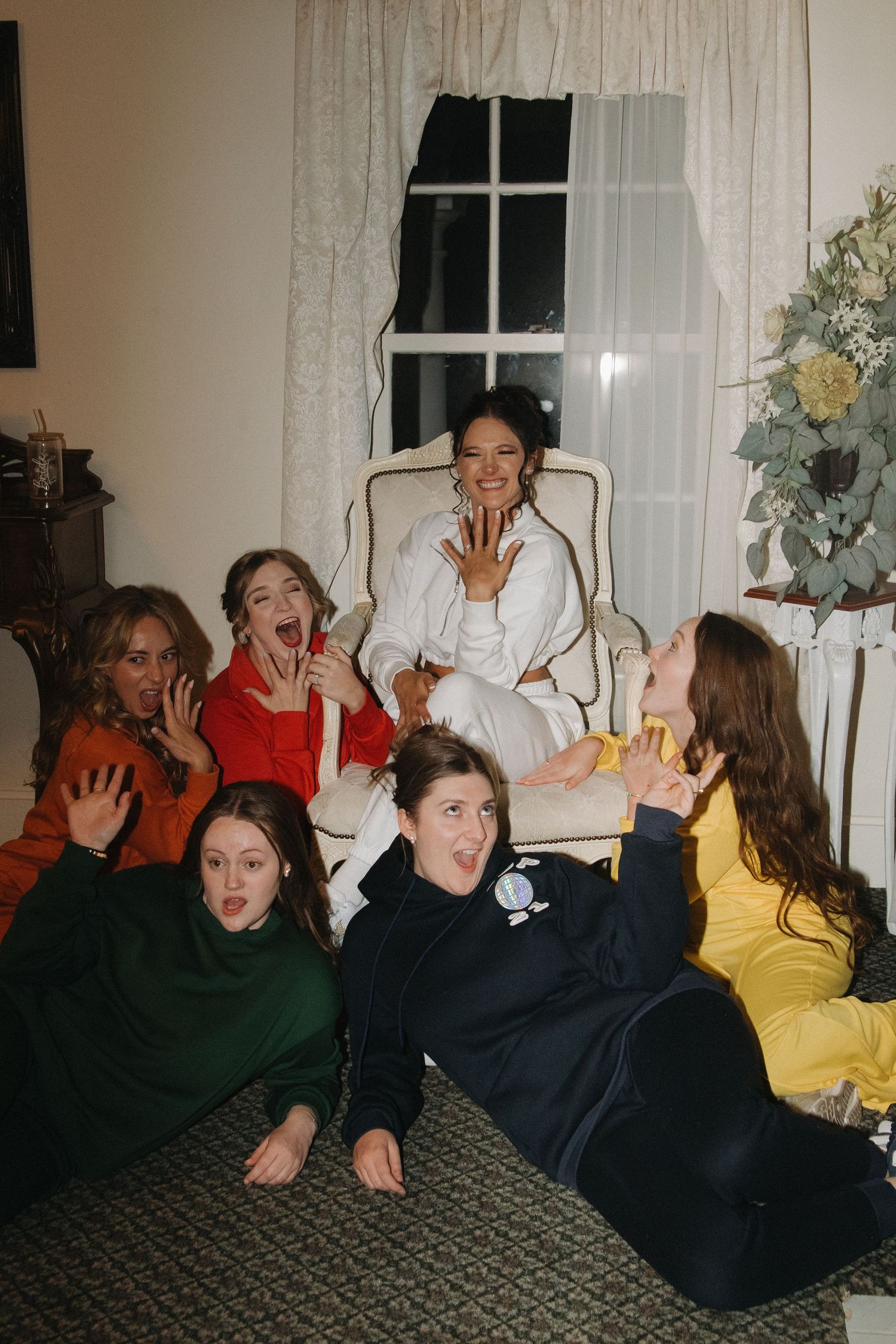 Group of wedding guests posing playfully on floor during evening celebration.