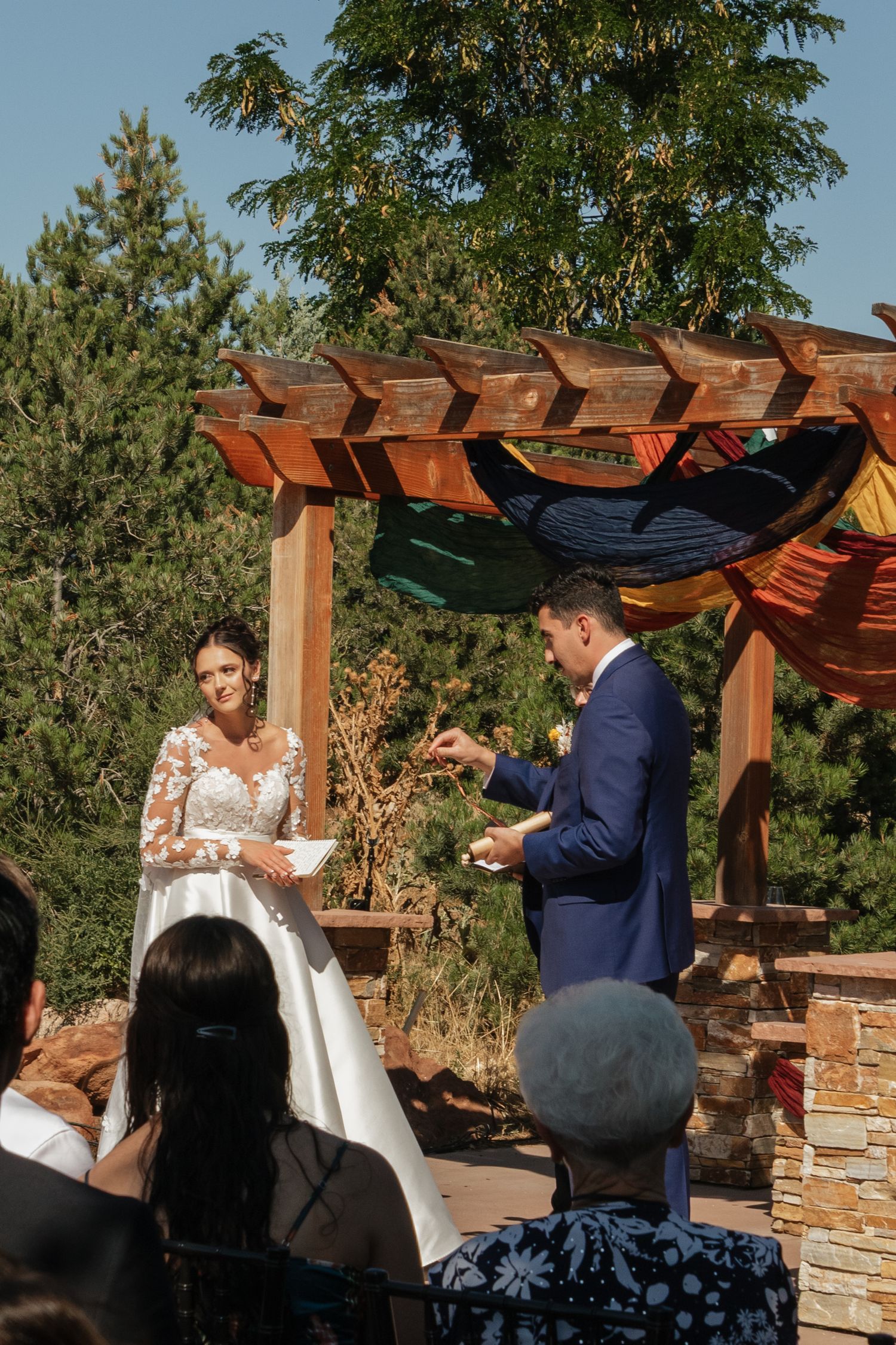 A sequence showing a wedding ceremony under a wooden pergola with mountain views.