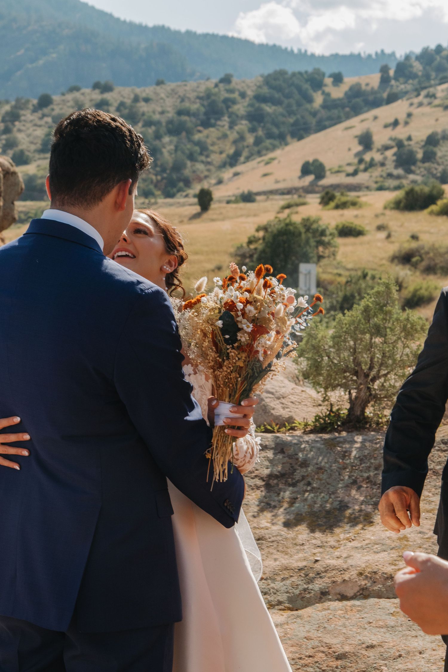 Romantic couple embracing against mountain landscape backdrop at wedding.