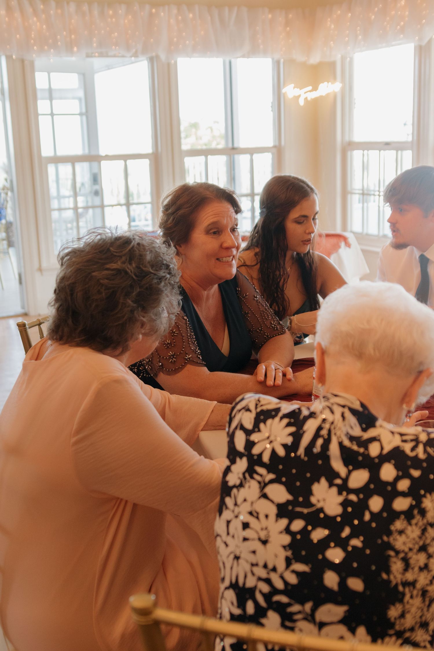 Wedding reception guests in black and white floral dresses enjoying the celebration.