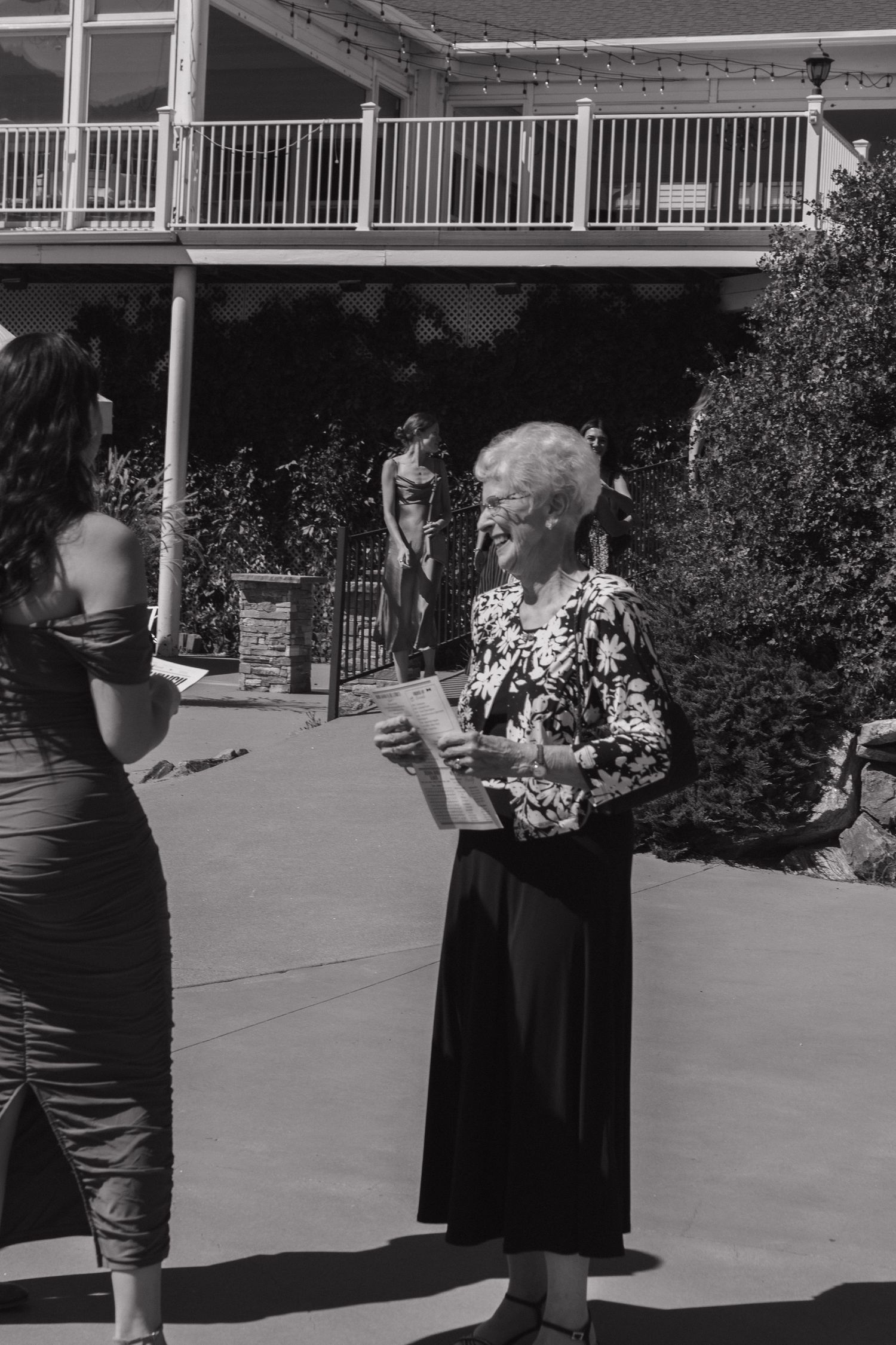 A gathering on an outdoor patio beneath a white railing during a wedding celebration.