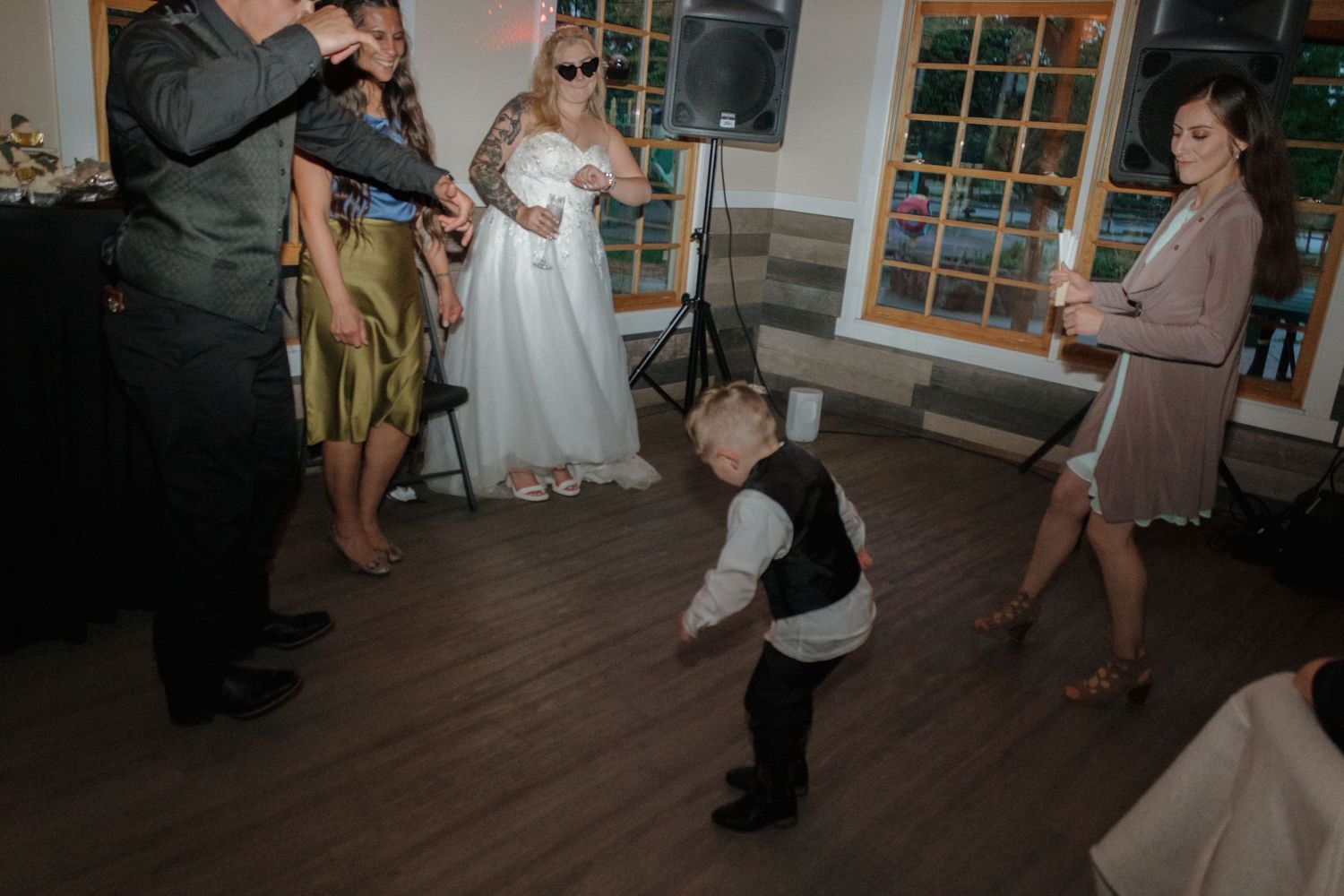 Wedding party dancing and celebrating on a dark hardwood dance floor.