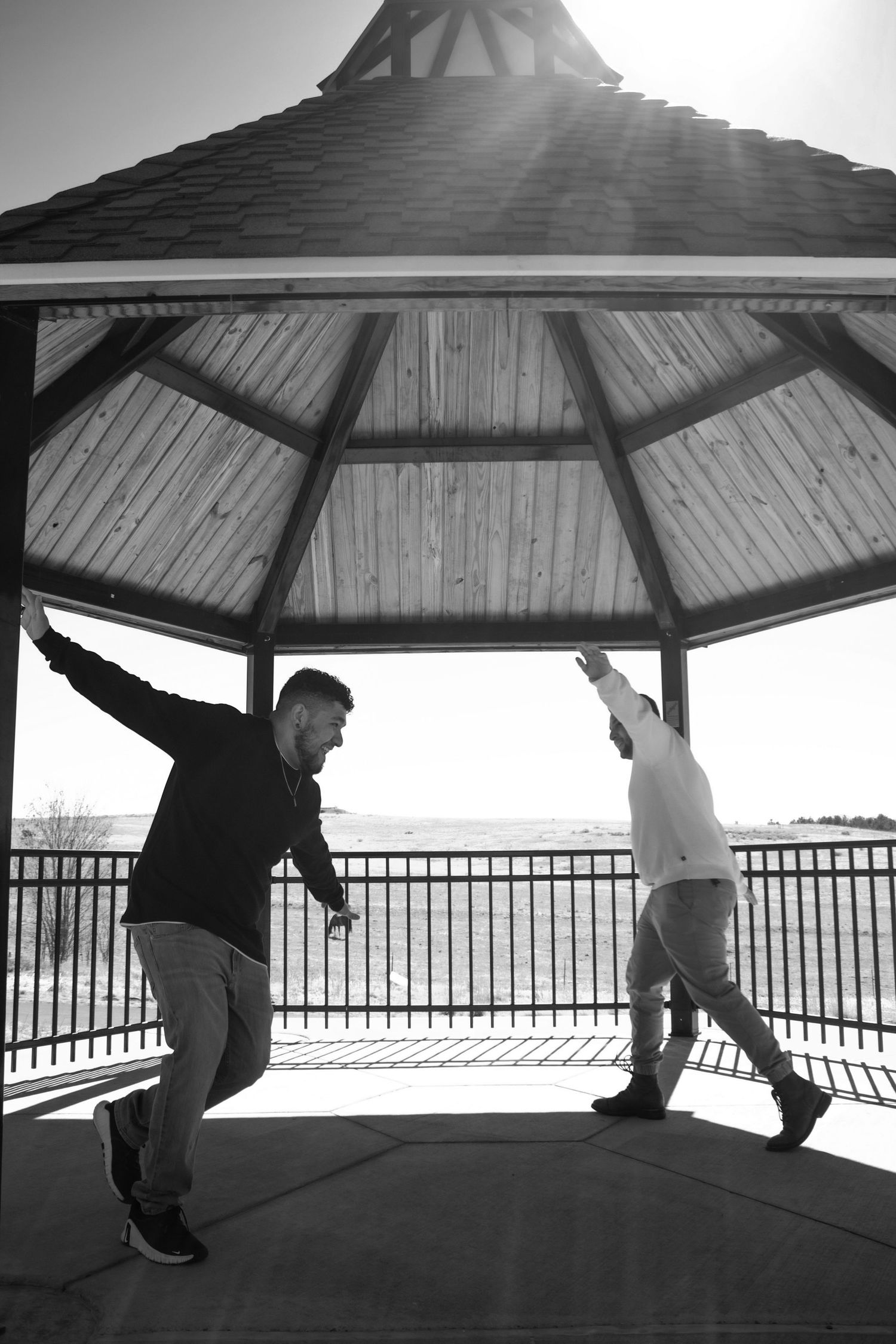 Black and white photo of two people dancing in a gazebo with sun flare.