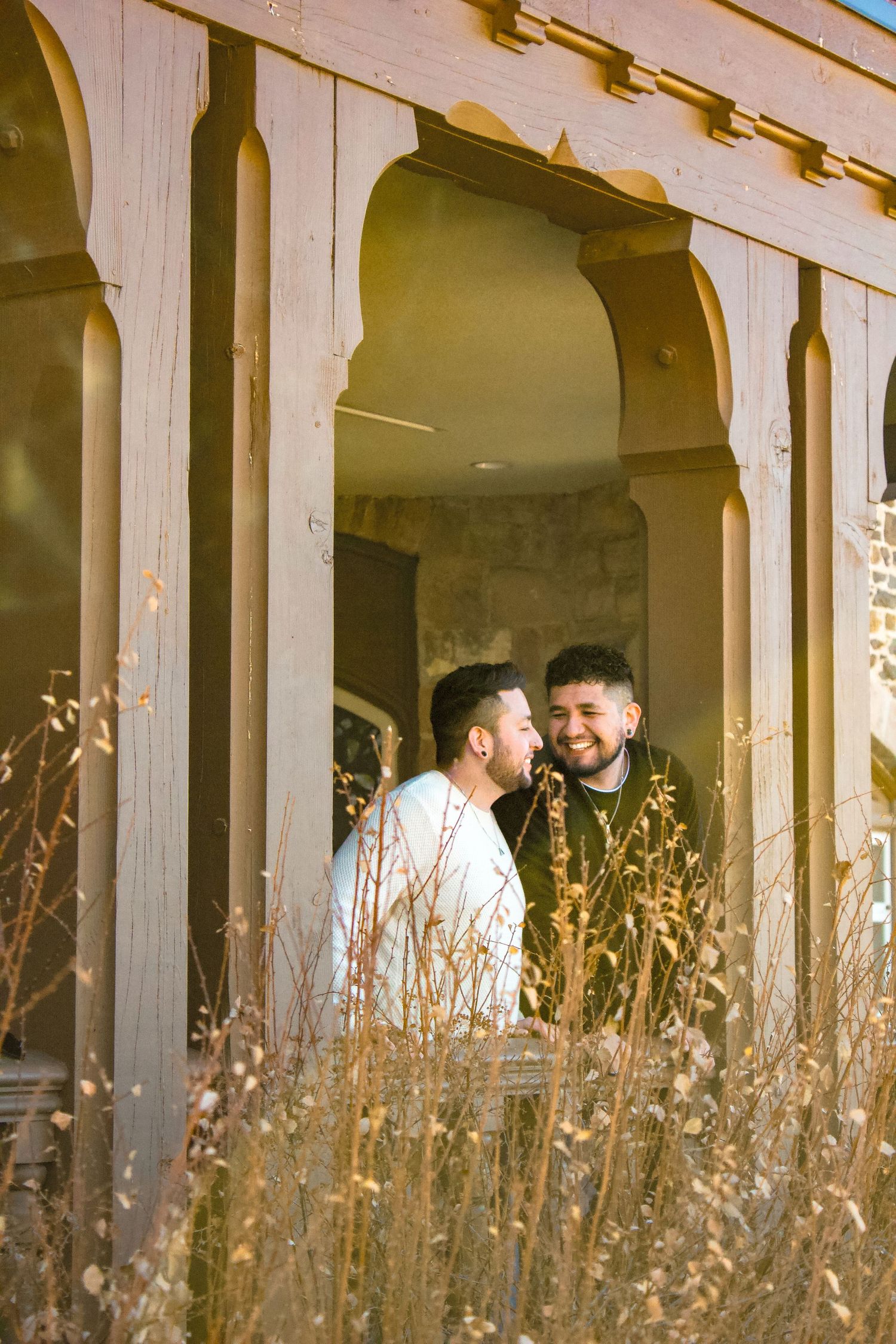 Intimate portrait through stone colonnade with golden dried grass in warm sunlight.