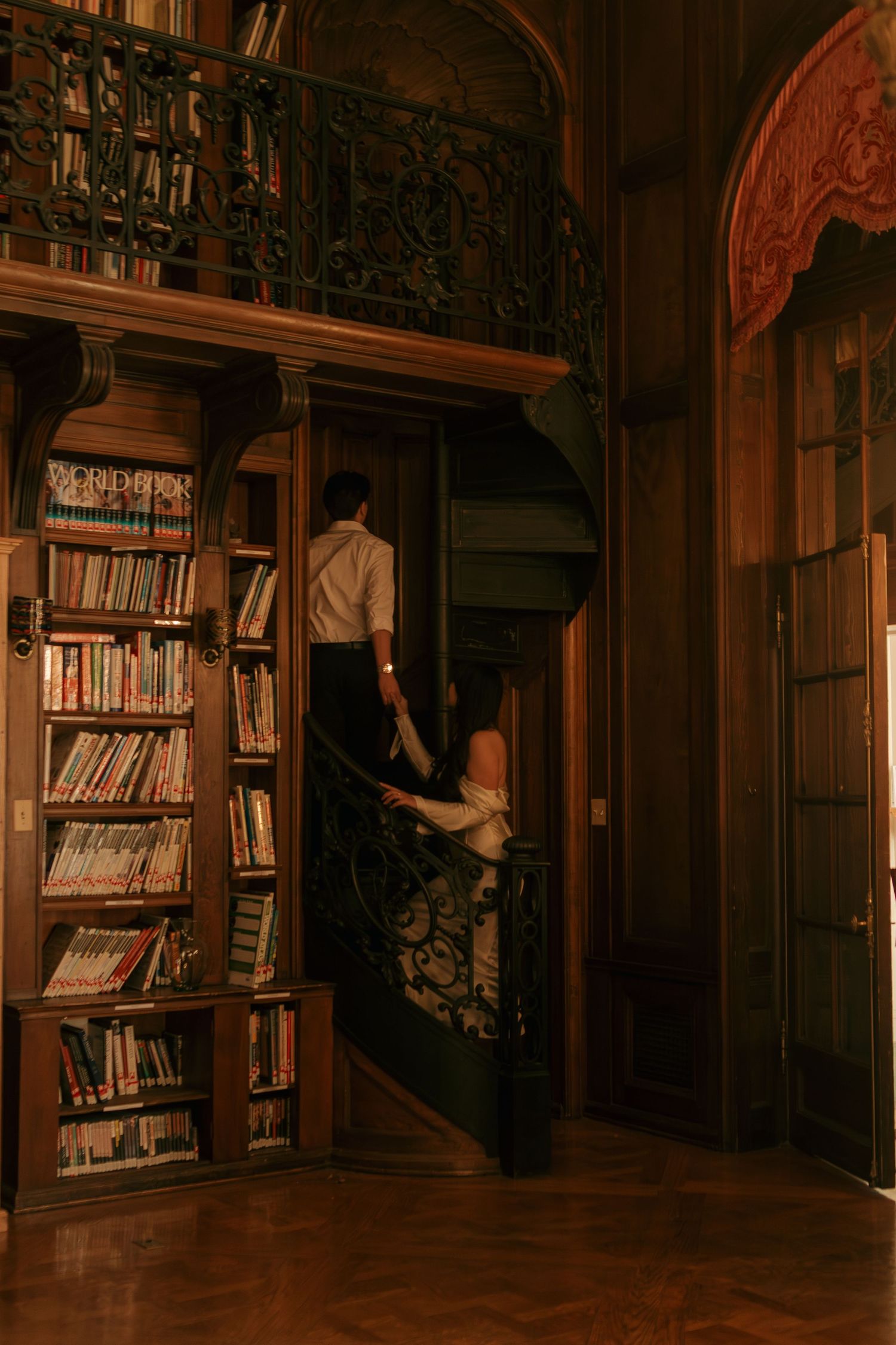 Wide view of an elegant library interior with carved wooden details and filled bookshelves.