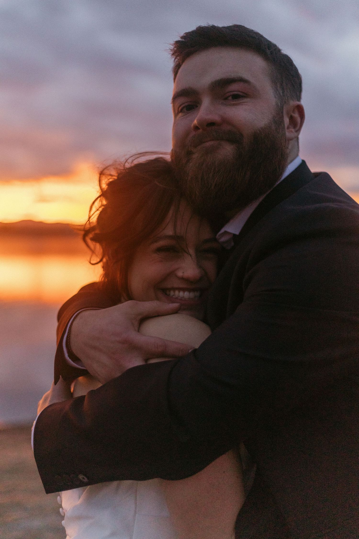 A couple embracing during sunset with warm golden light creating a silhouette effect.