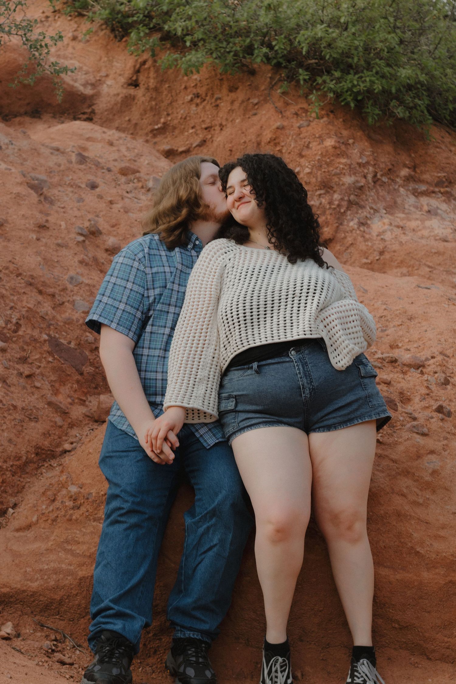 A tender moment between a couple against red rock formations in warm lighting.