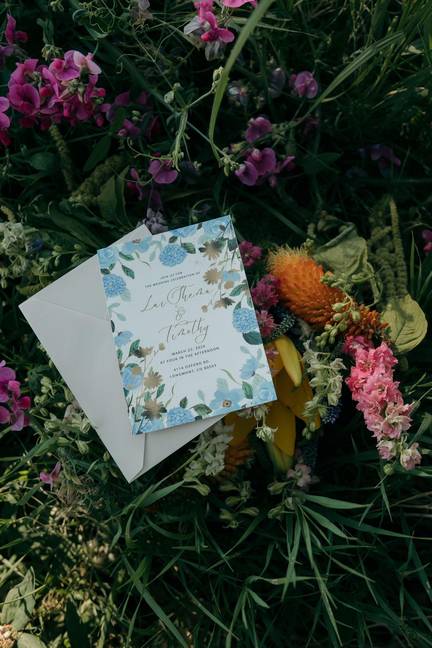 Floral wedding invitation for Lee-Marina and Timothy displayed among colorful wildflowers and greenery.