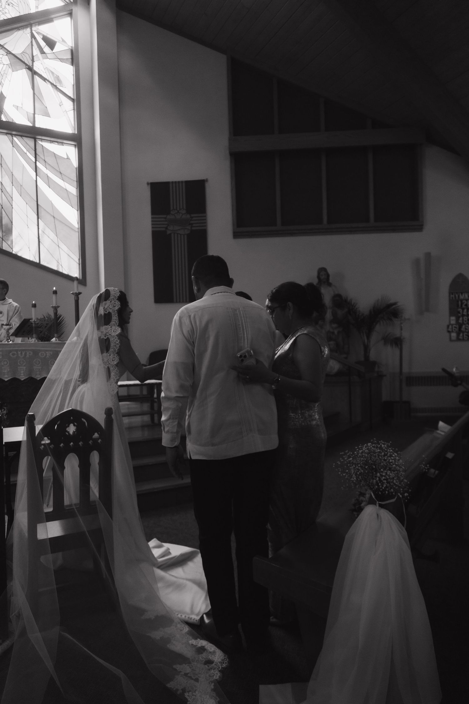 Black and white photo of bride and groom standing at church altar during wedding ceremony.