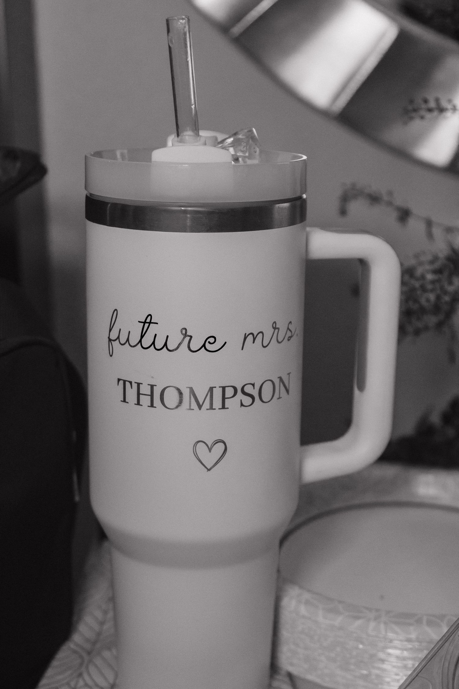Black and white photo of a Stanley tumbler engraved with future mrs Thompson and a heart.