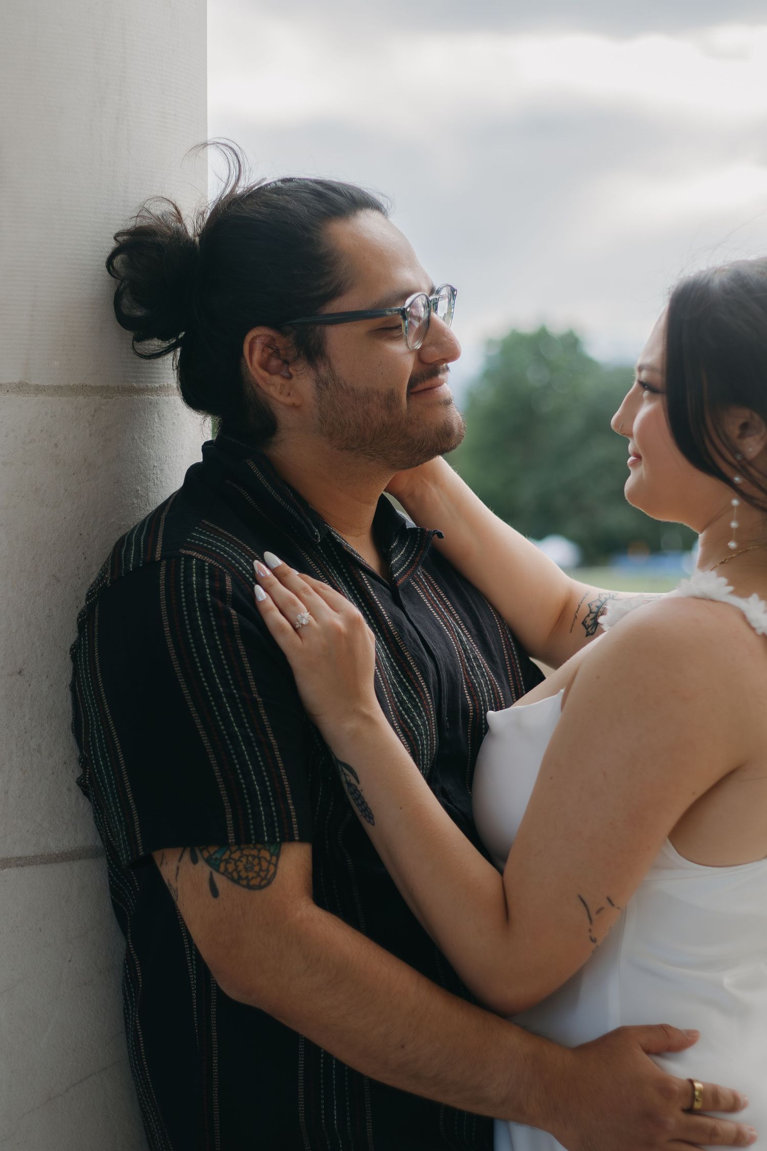 A tender moment between a couple against a wall with soft outdoor lighting.