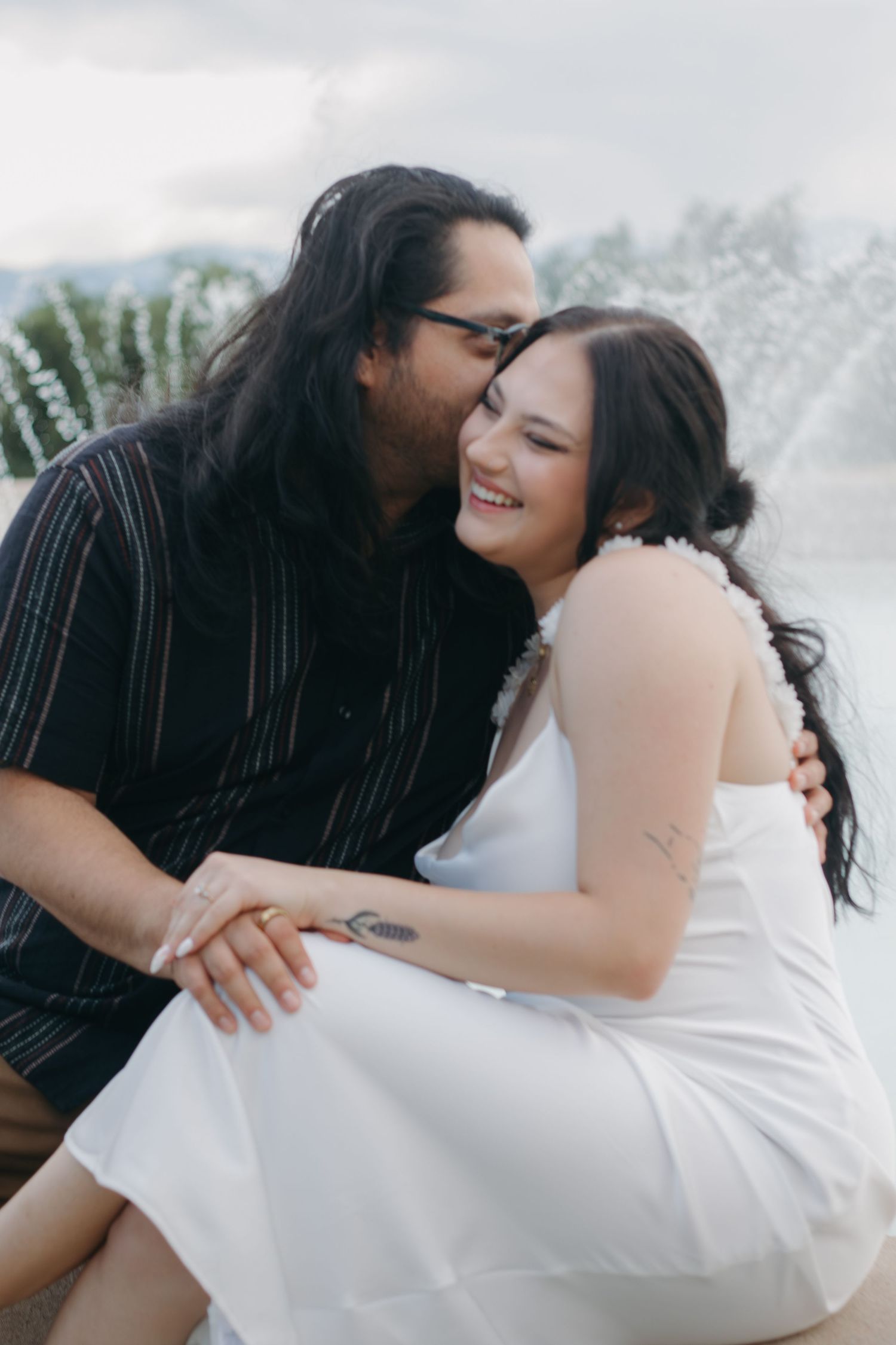 Intimate wedding portrait with couple sharing a joyful moment near fountains.