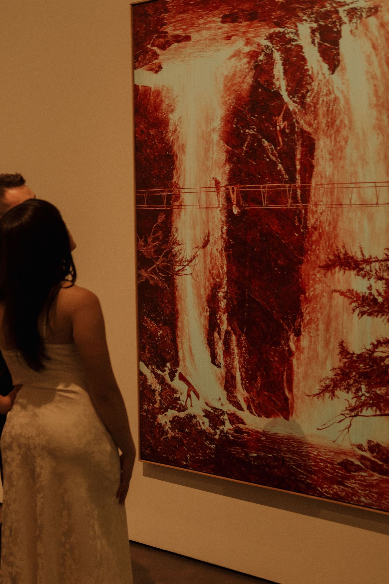 Person views large abstract artwork depicting a dramatic waterfall scene in museum gallery.