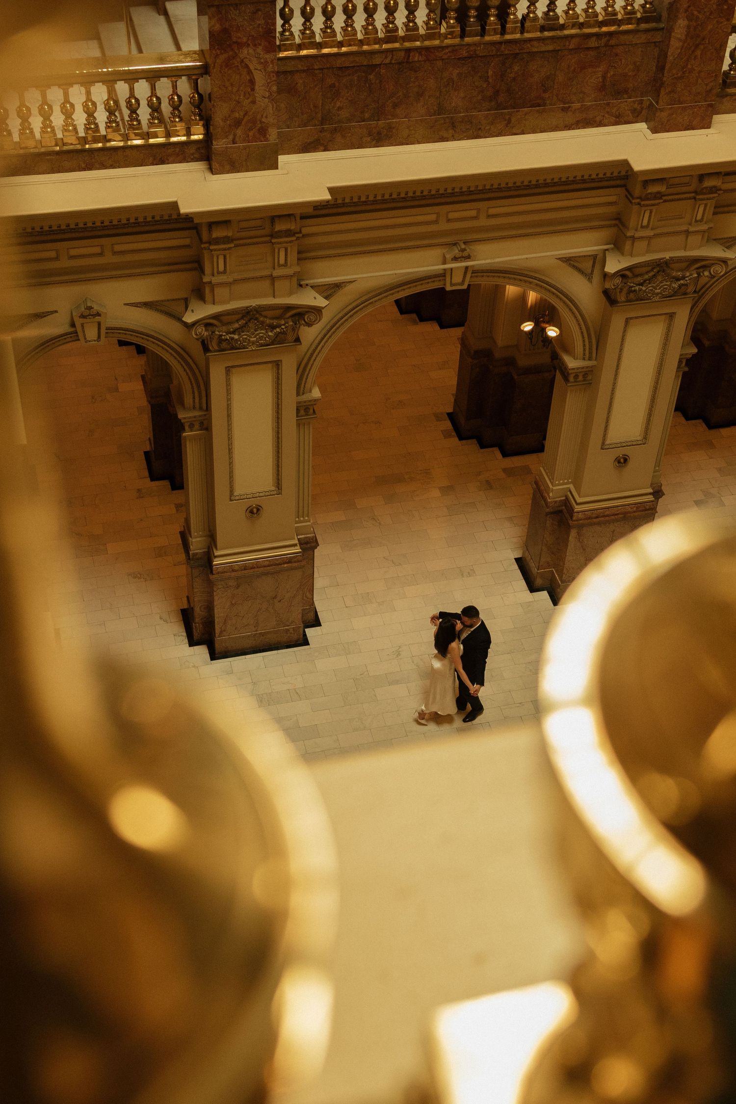 Dancing couple silhouetted in grand historic building with ornate architecture.