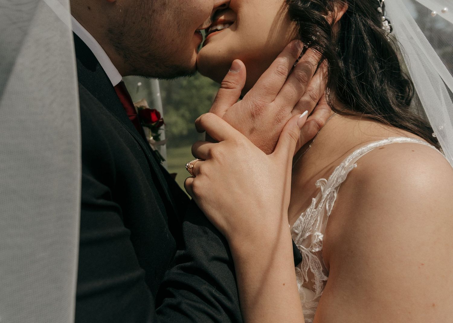 Close-up of groom tenderly holding bride's face as they share a romantic almost-kiss moment.