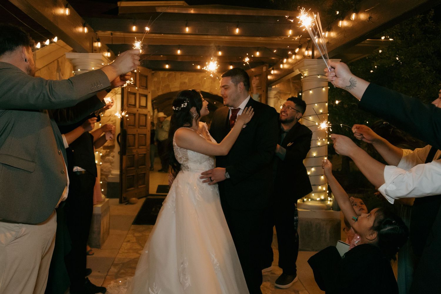 Bride and groom share a romantic dance surrounded by guests holding sparklers at their wedding reception.