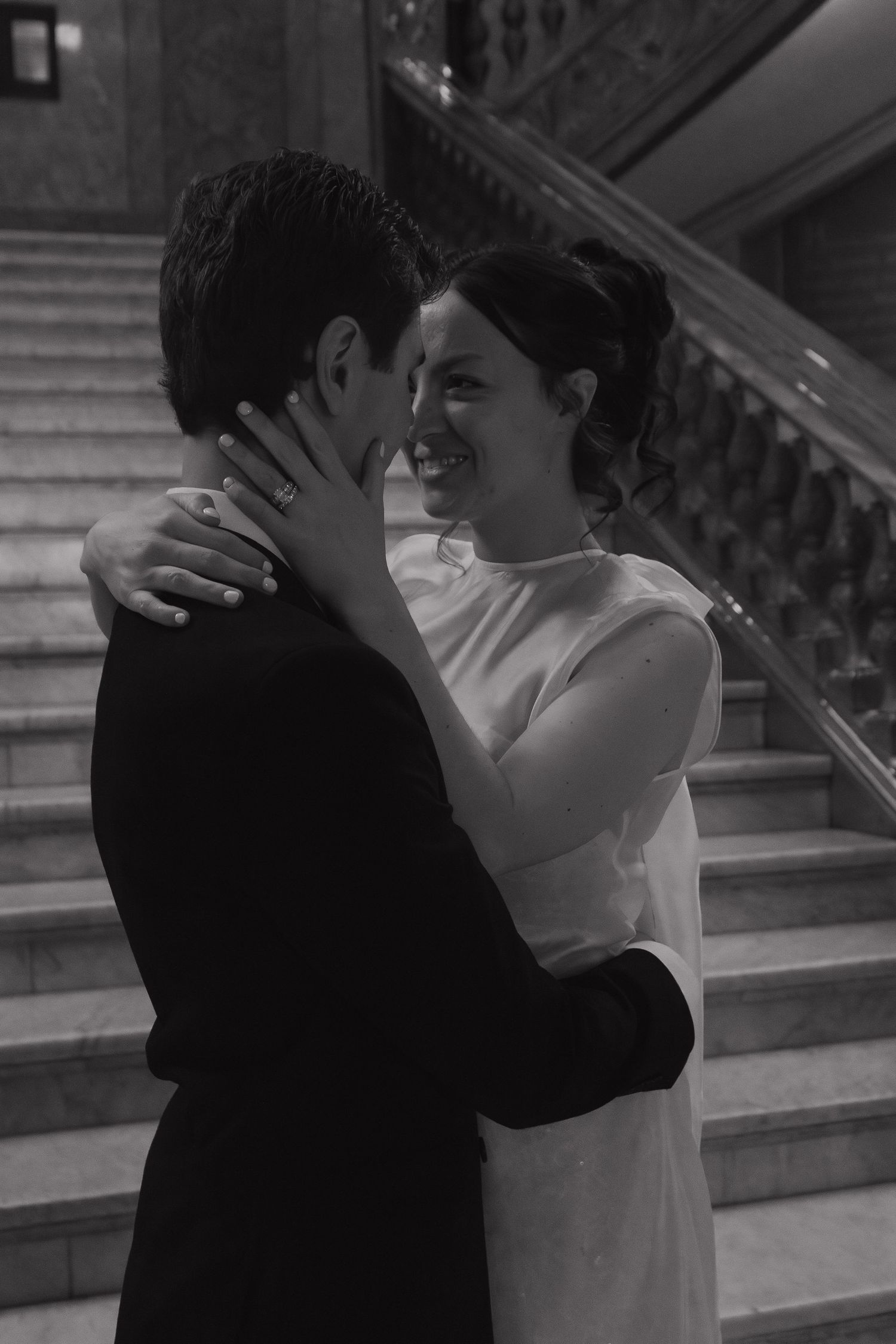 Black and white photo of intimate wedding moment on historic building steps.