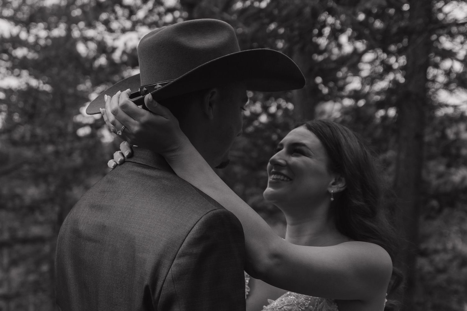 A tender wedding moment captured in black and white against a forest backdrop.