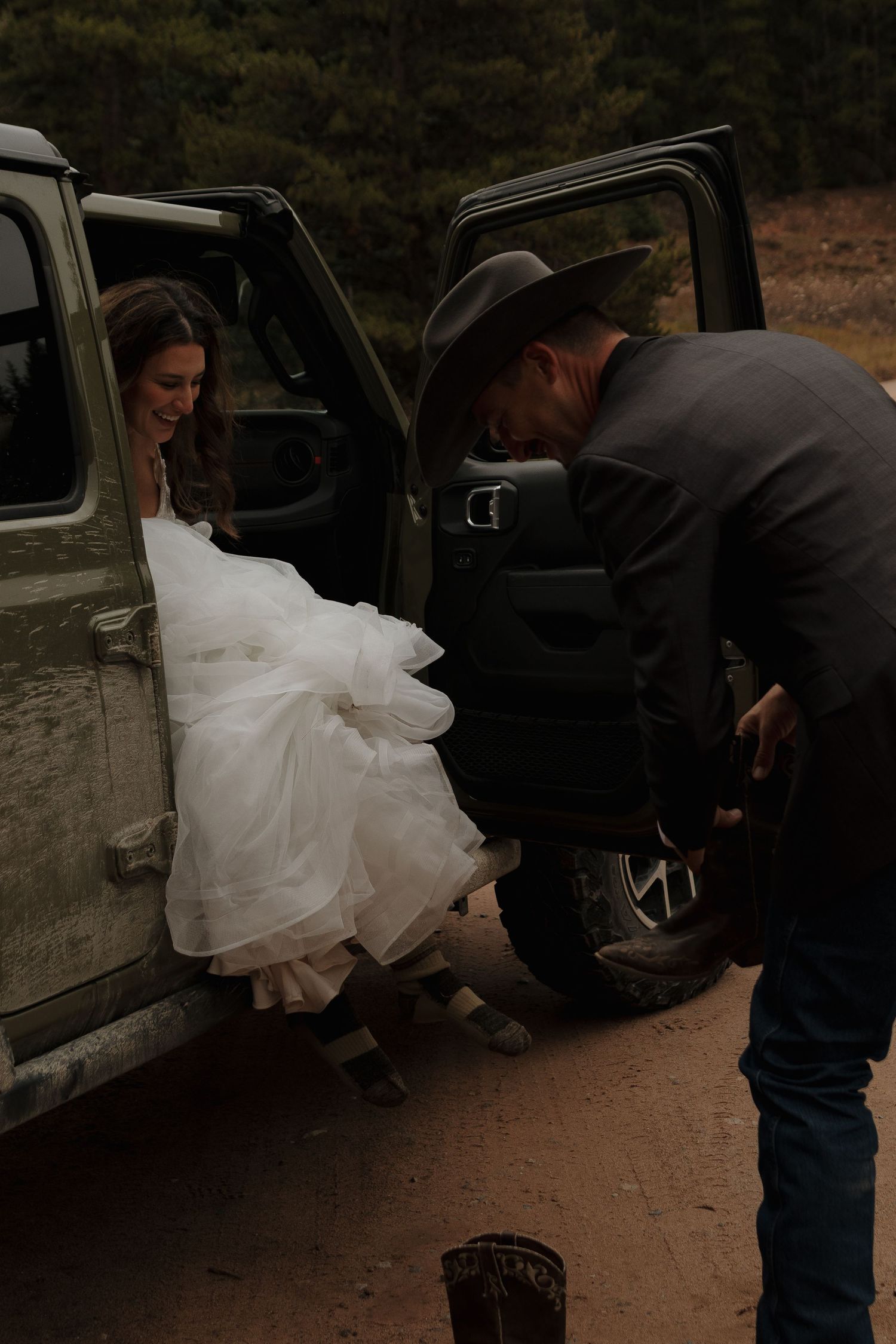 A cowboy helps his bride exit a vehicle on their wedding day.