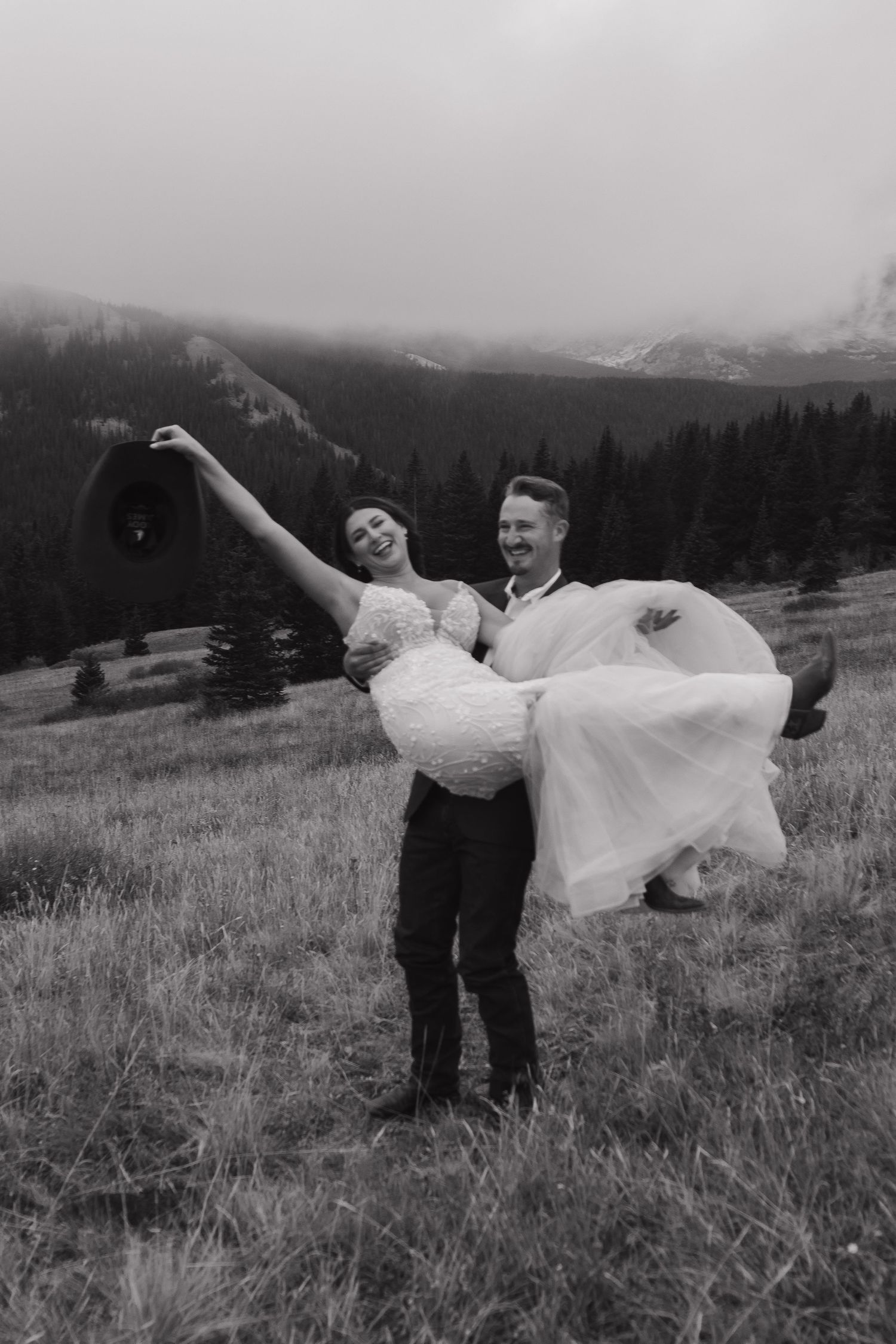 A joyful lift pose captured in black and white against a mountain landscape.