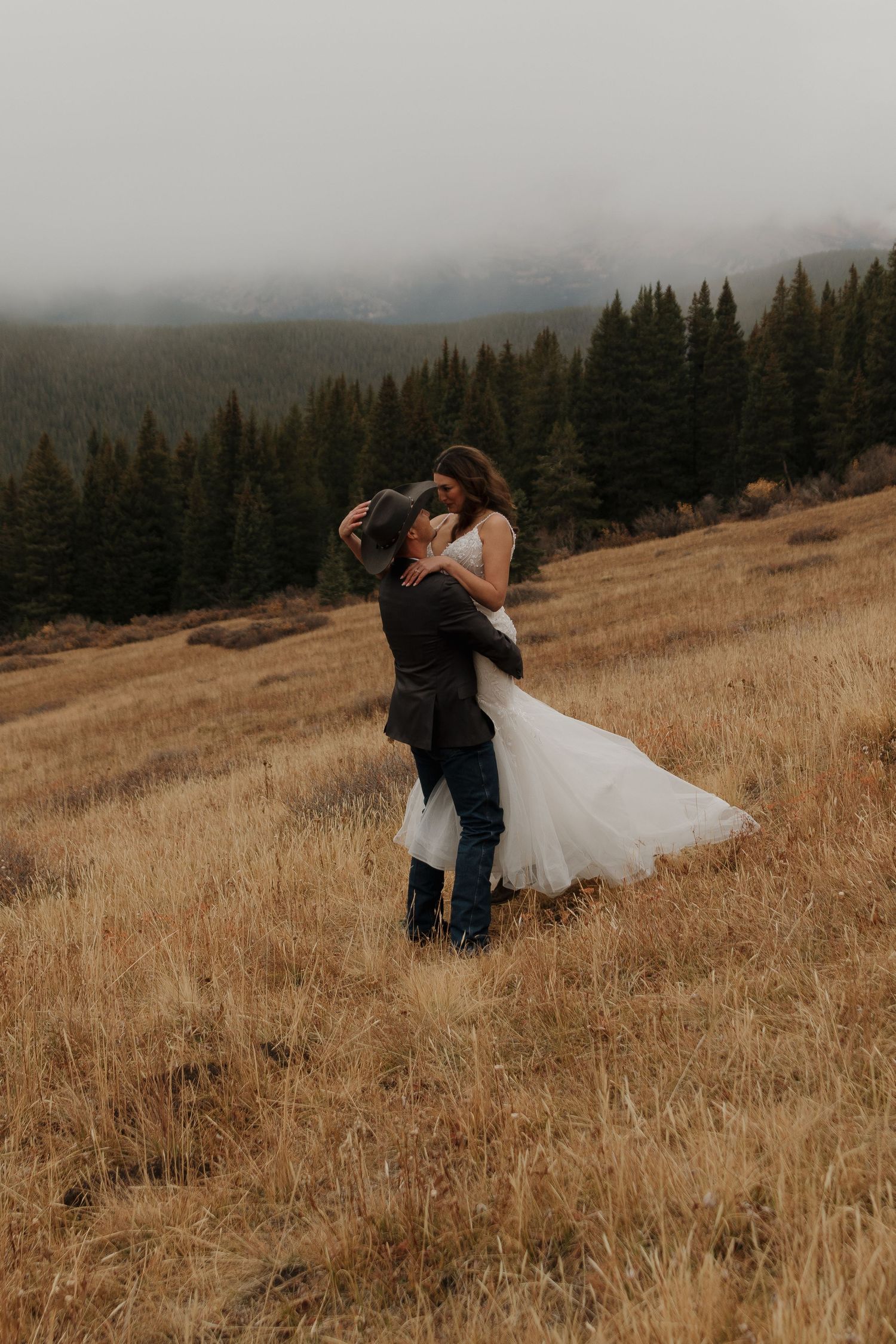 A romantic embrace between newlyweds in a golden mountain meadow.