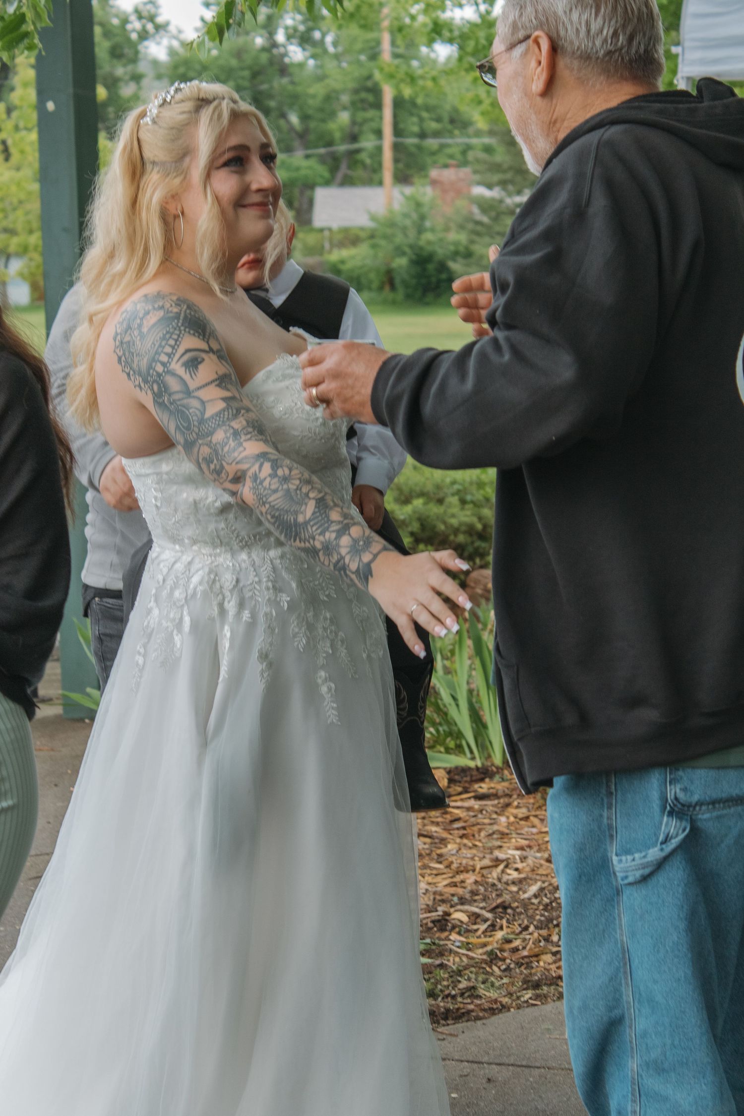 Emotional embraces being exchanged at an outdoor wedding ceremony under a white tent.