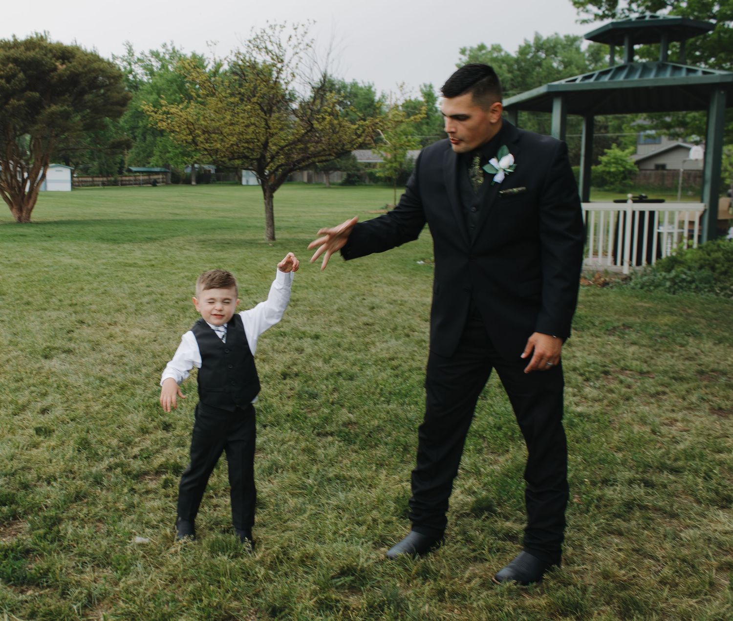 Playful wedding moments captured on grassy lawn near gazebo.