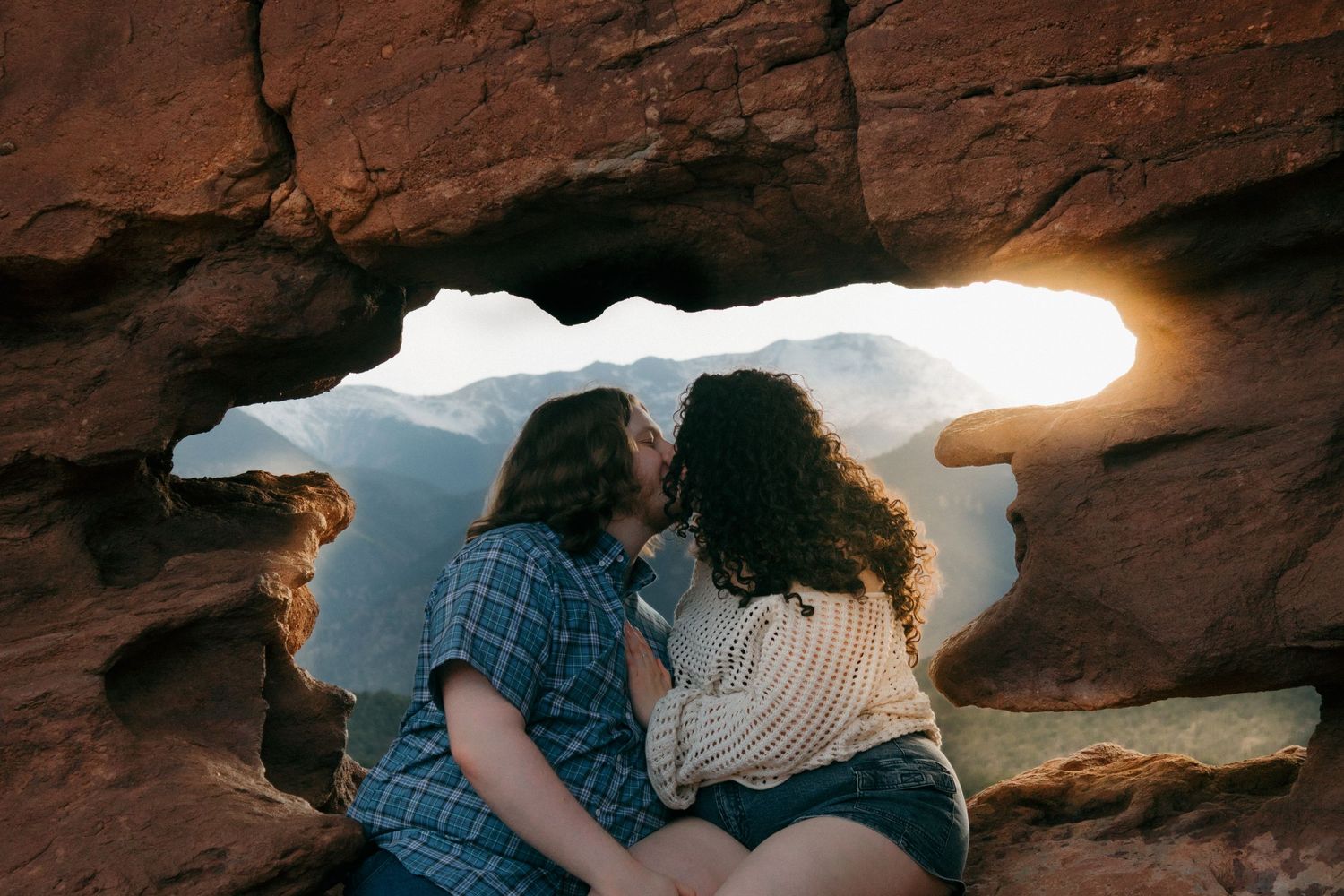 Desert landscape photo with couple framed by dramatic rock formation opening.