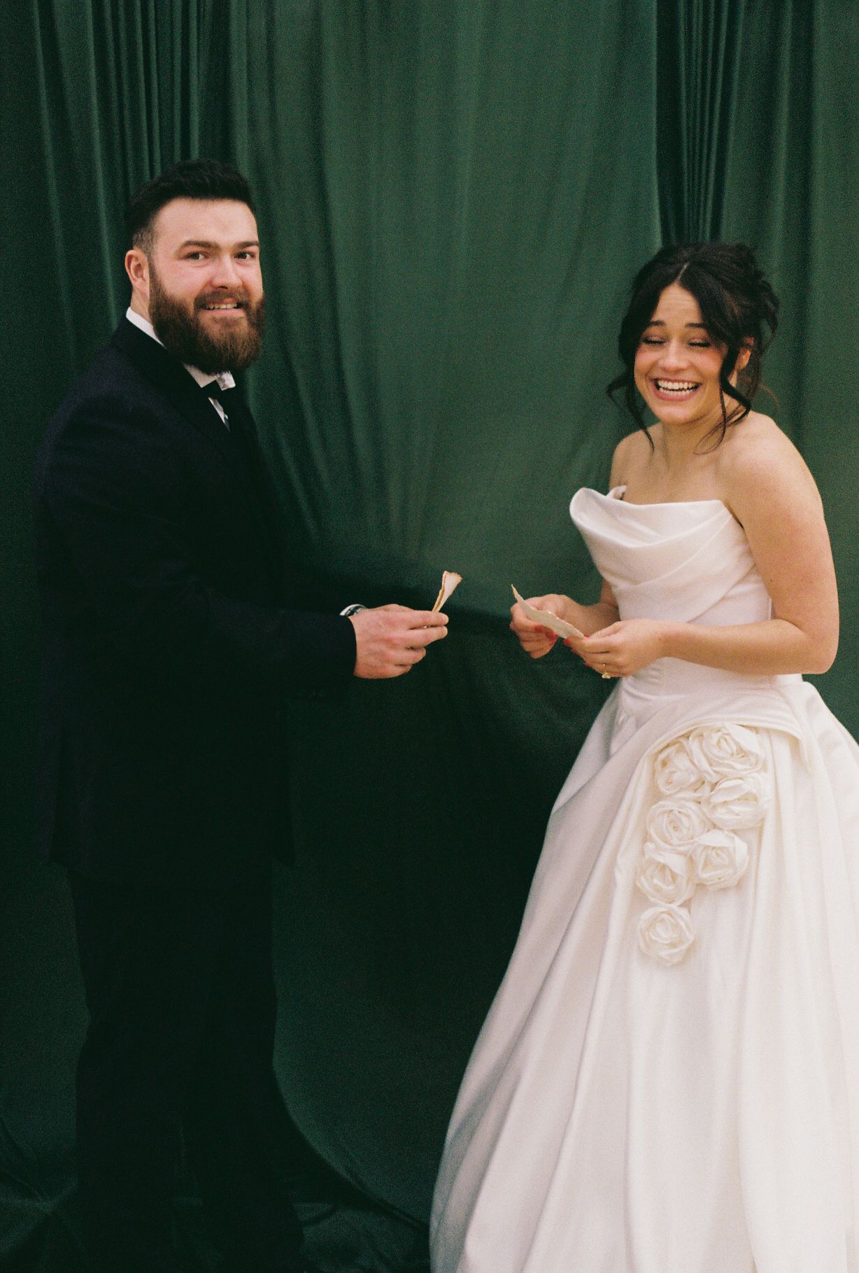 A couple exchanges vows against a dark green backdrop during their wedding ceremony.