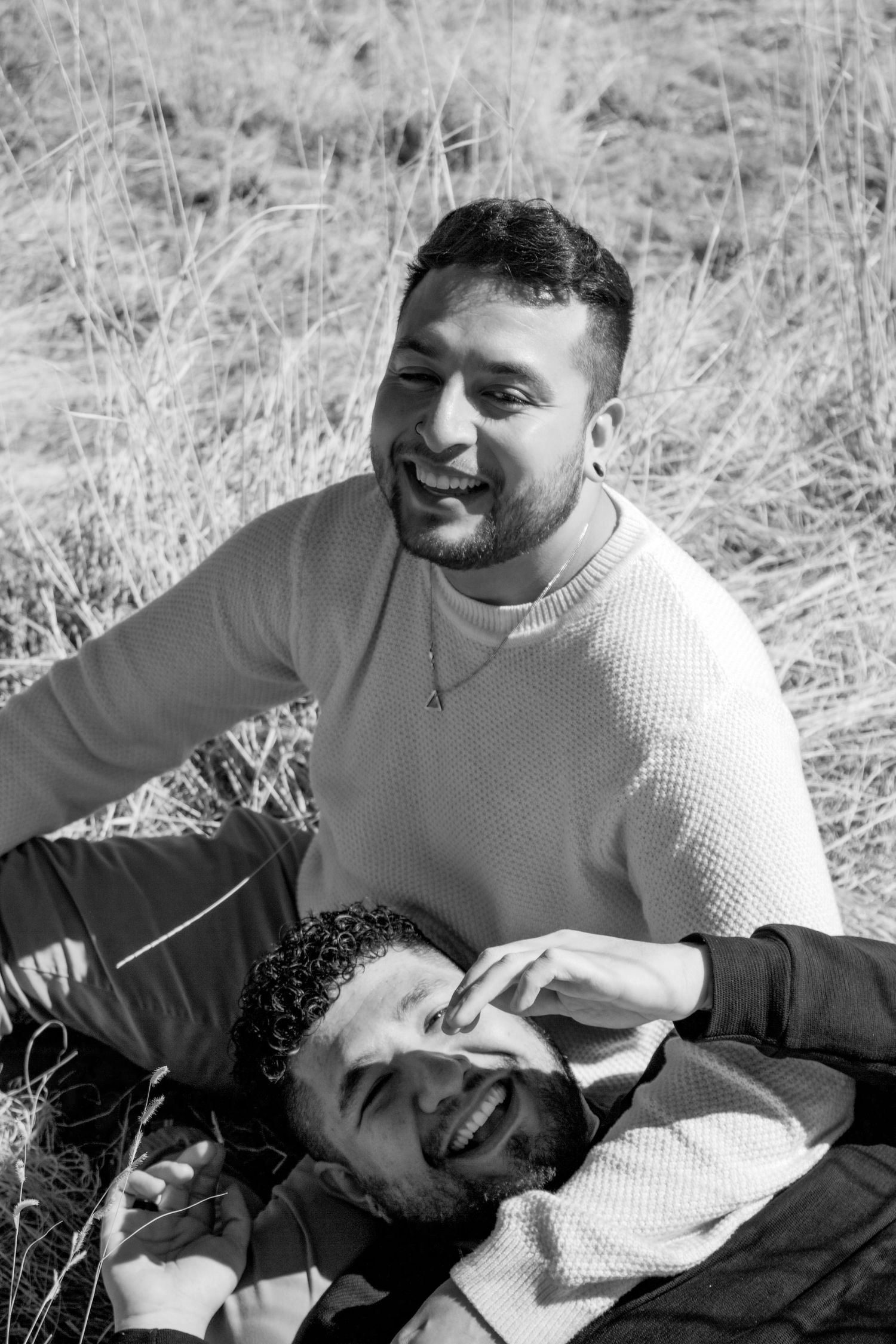 Black and white portrait of two people sharing joyful moment in field.