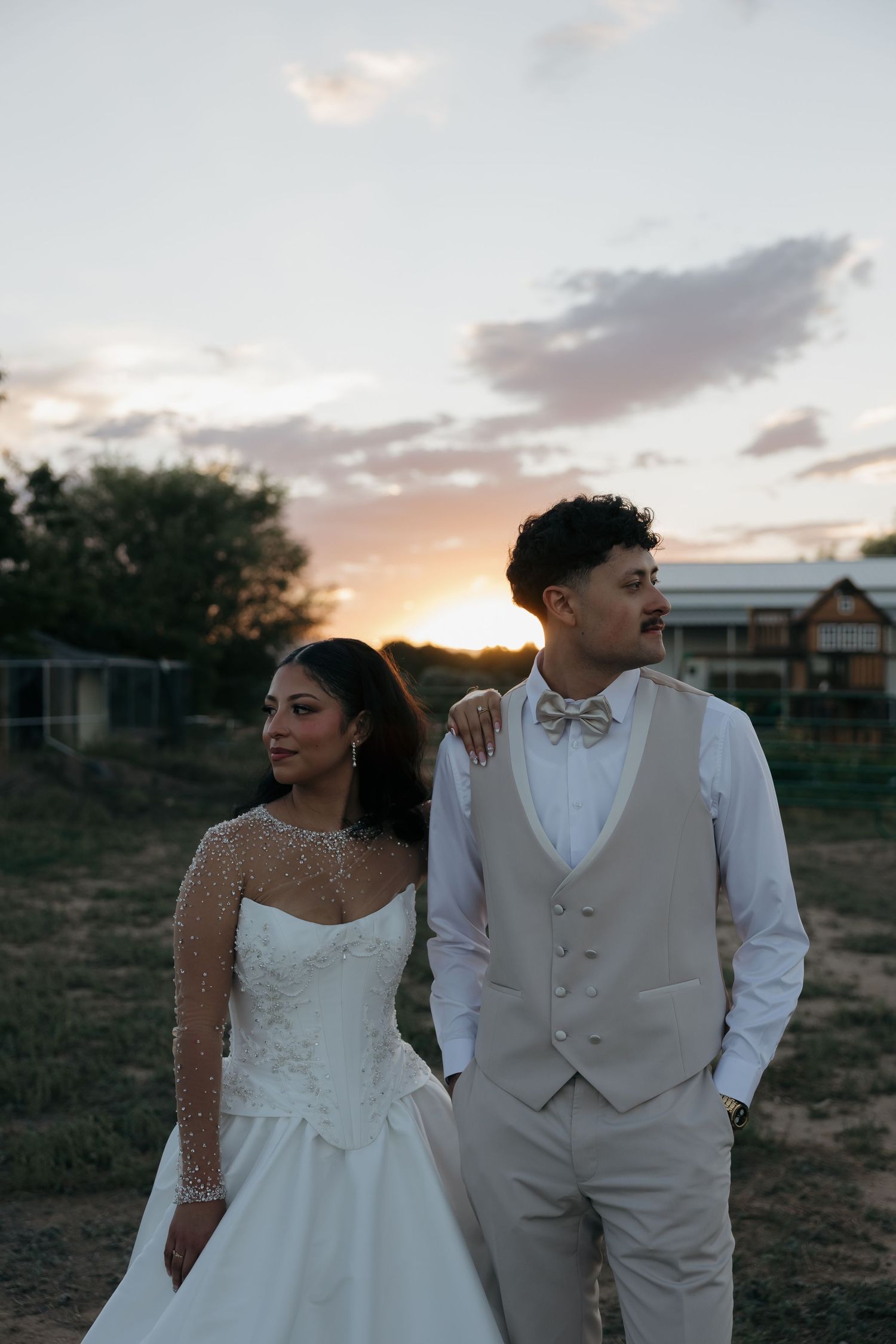 A bride and groom share a romantic sunset moment outdoors at their rustic countryside wedding venue.