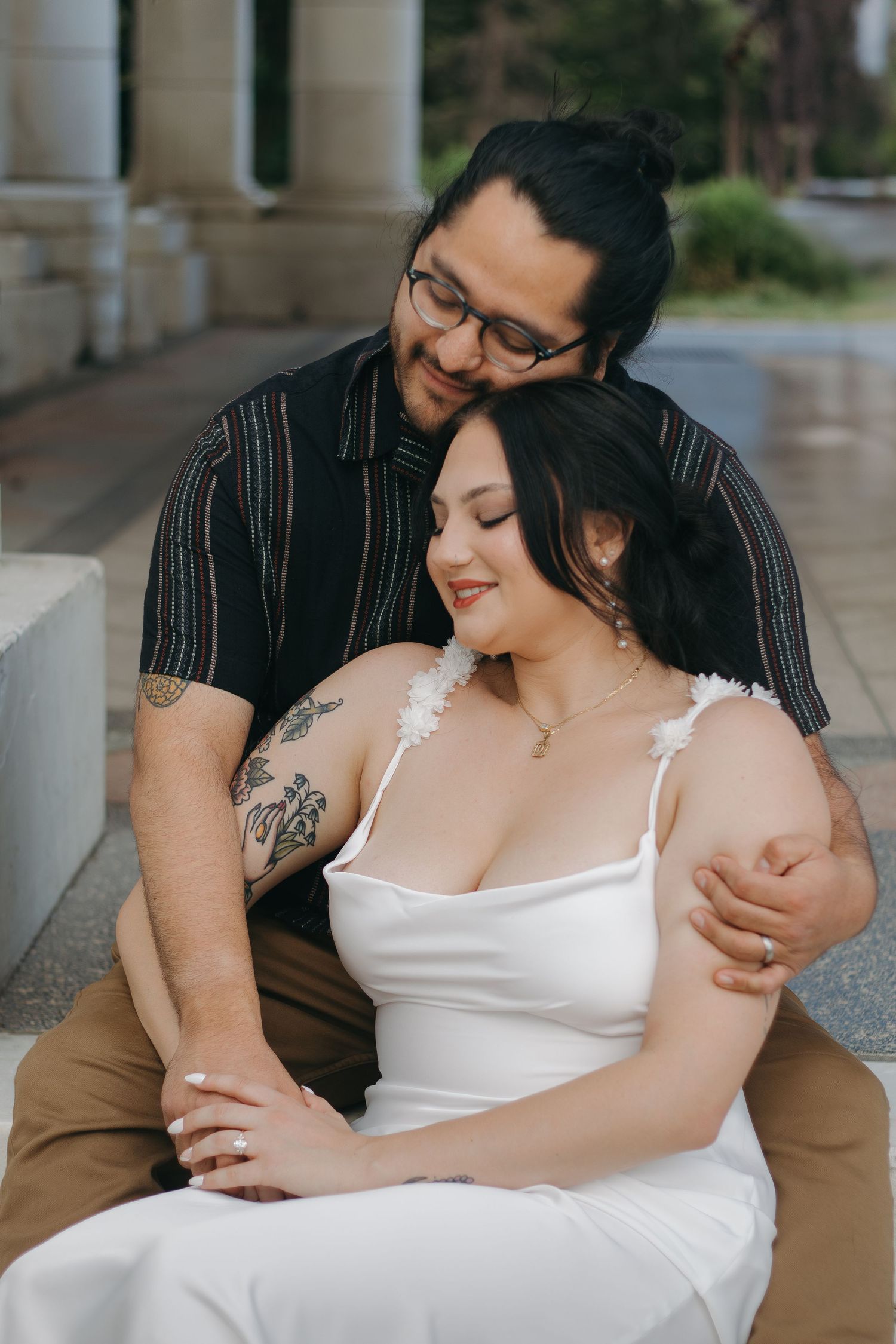 A romantic couple embraces in a white dress and dark shirt at an indoor venue.