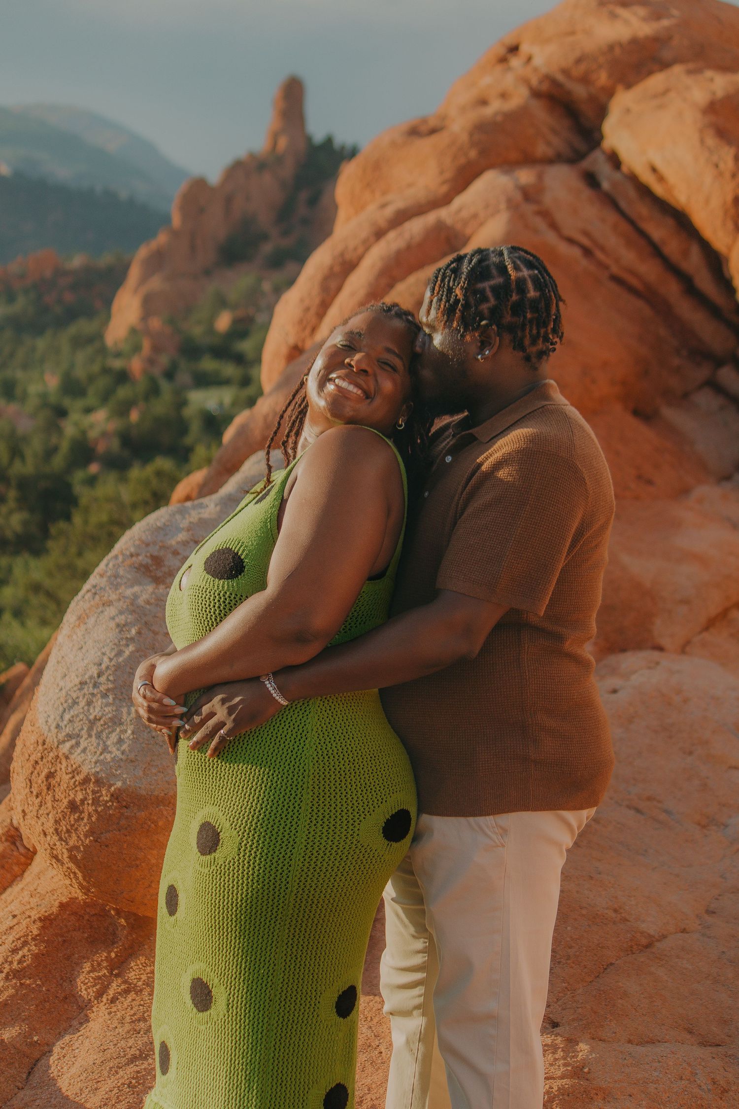 A tender moment shared at Garden of the Gods with red rocks and mountains in the background.