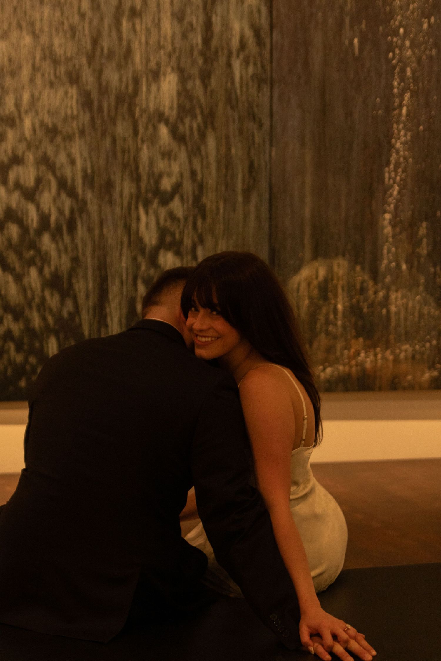 Two people share tender embrace in dimly lit space.