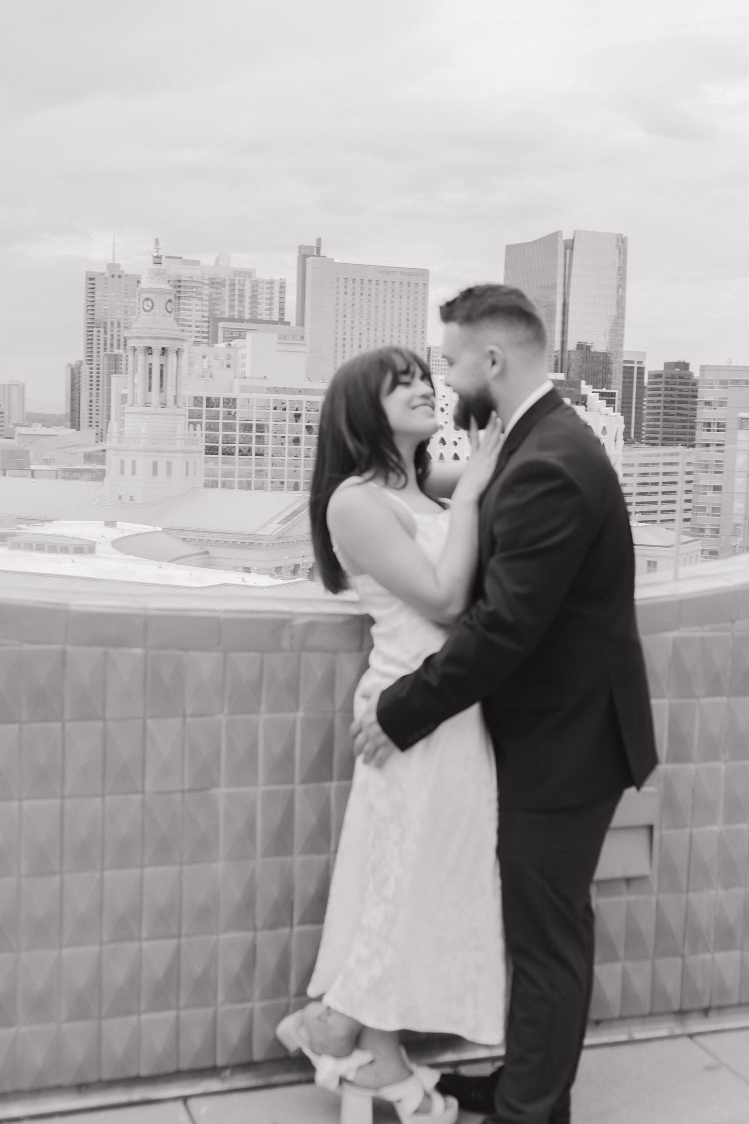 A romantic sequence of rooftop kisses with a city skyline backdrop in black and white.