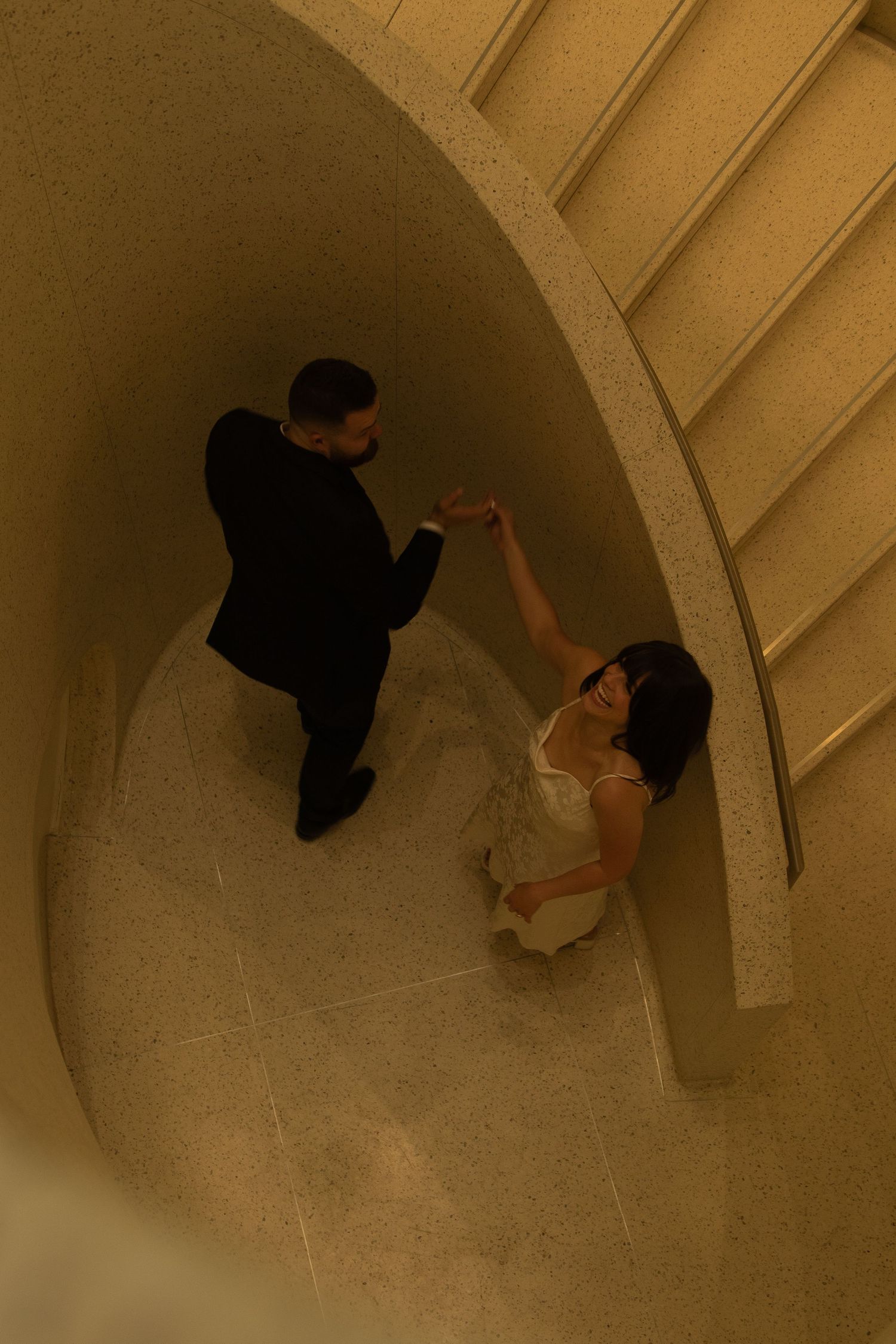 Dancing sequence captured from above in a spiral stairwell with sepia tones.