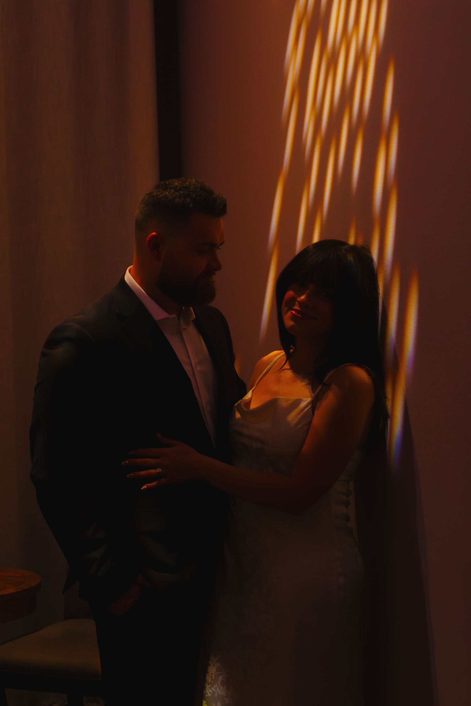 Silhouettes of figures in dramatic warm lighting against white curtains.