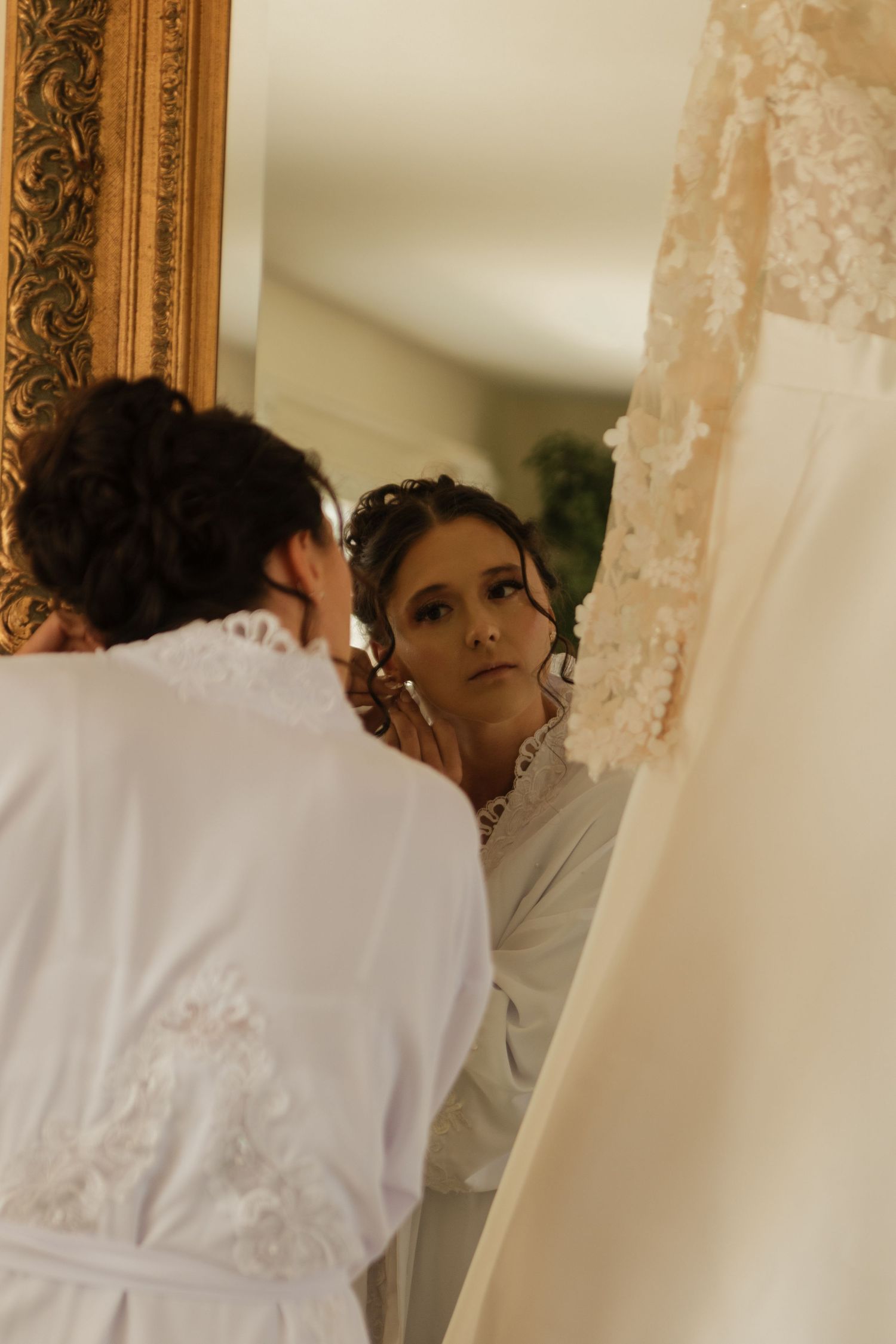 Getting ready on wedding day with bridal party surrounded by elegant lace curtains and robes.