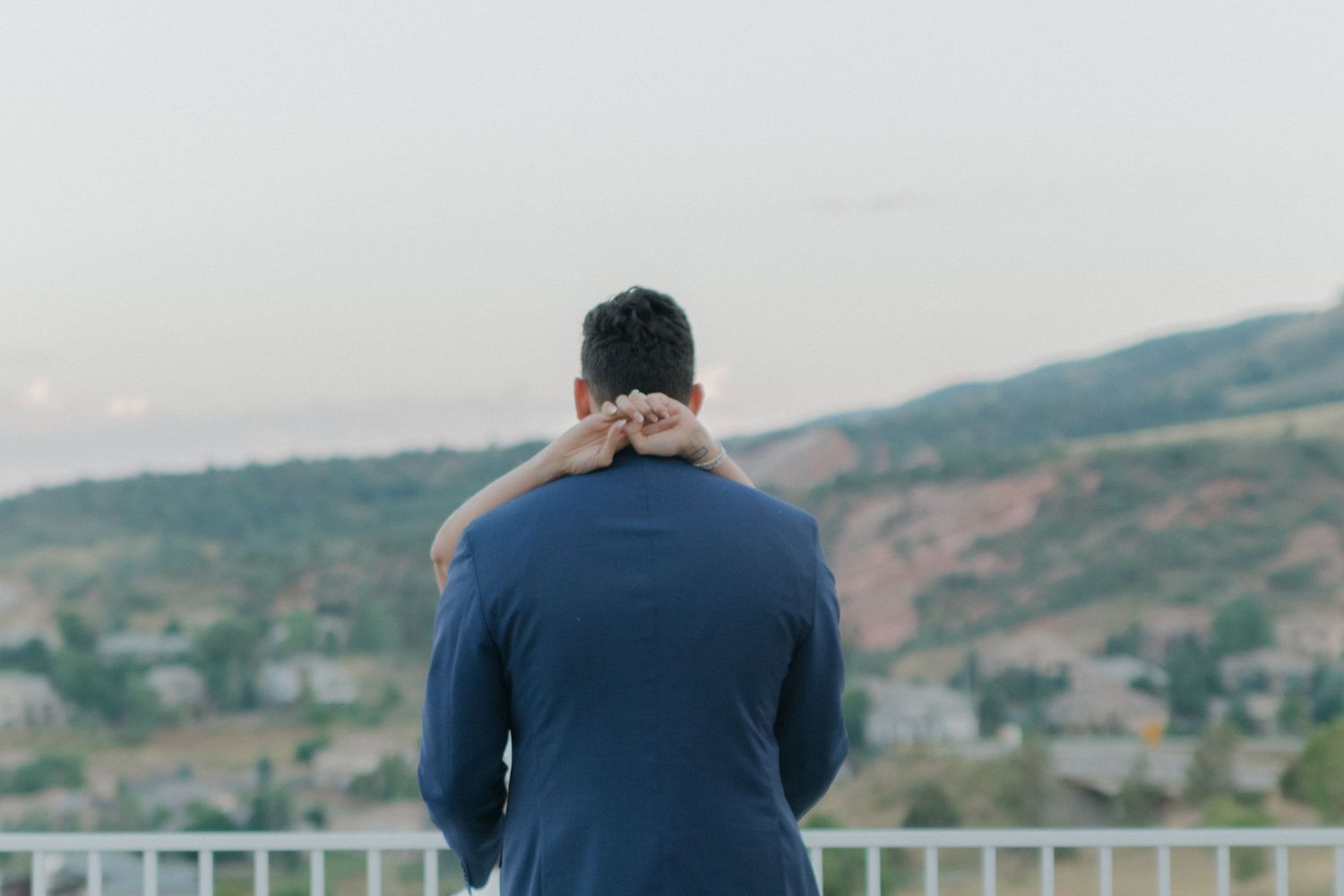 Person in navy suit looking out over mountain landscape view.