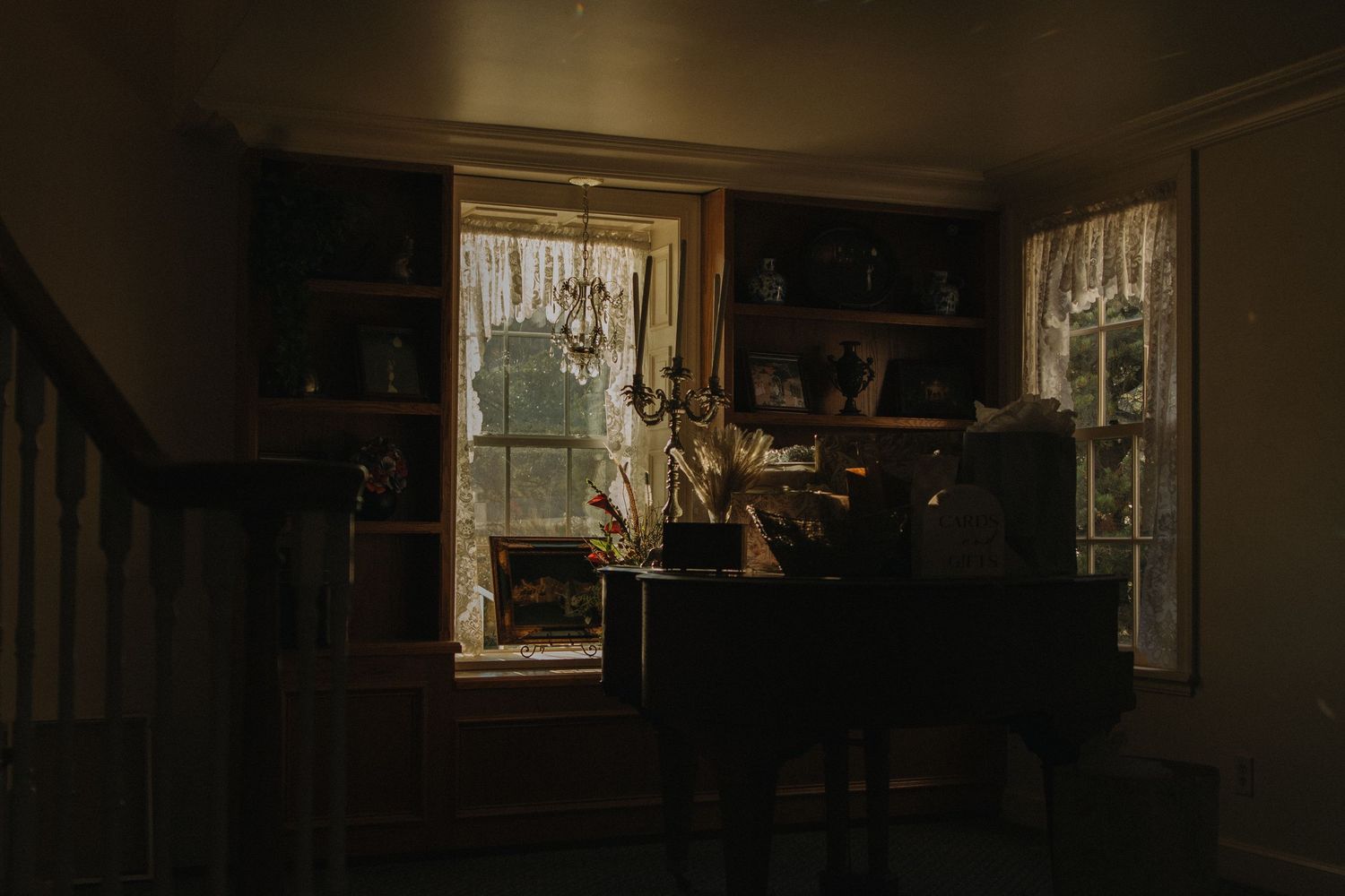 Dark interior room with sunlight streaming through windows during wedding preparations.