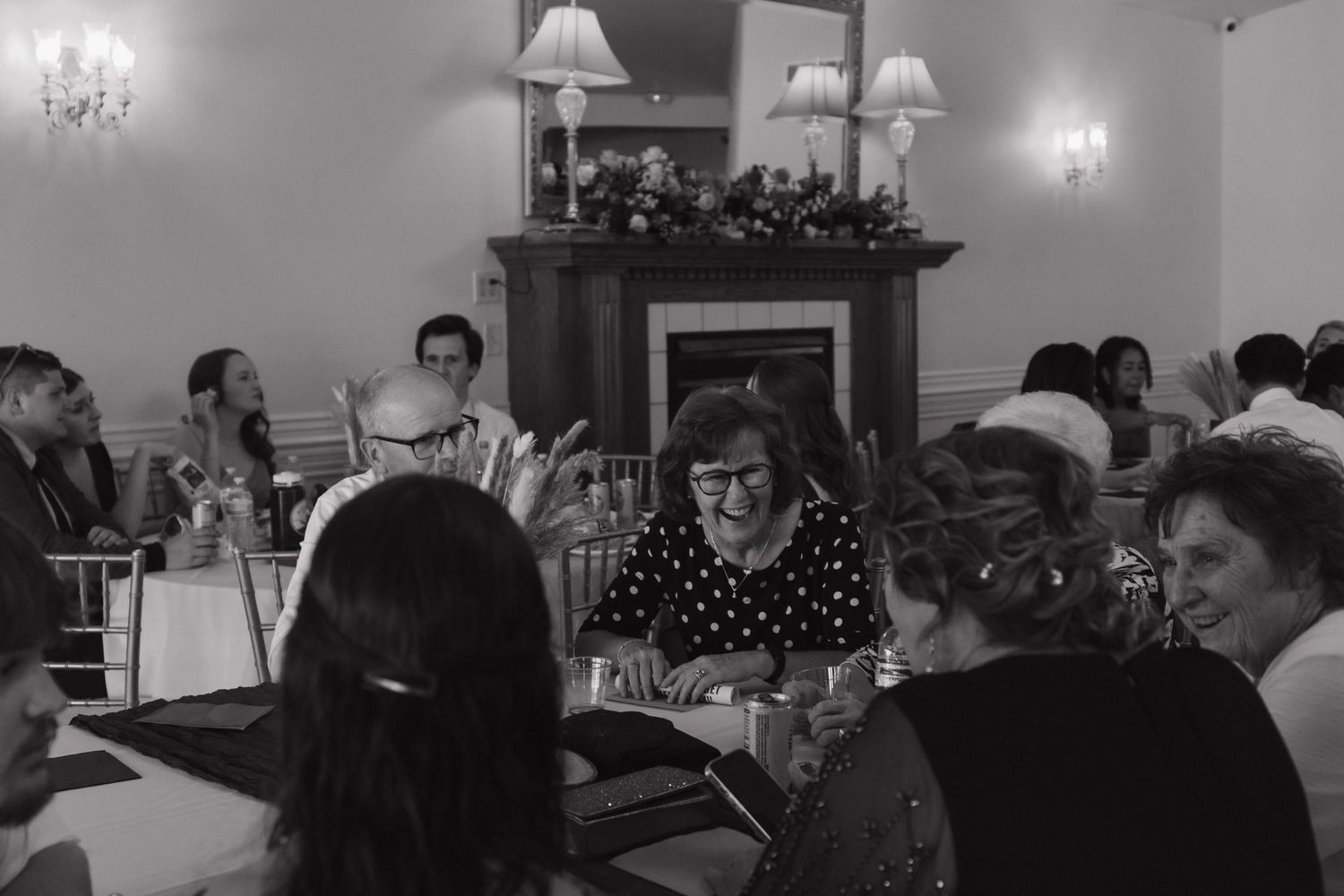 Wedding reception venue with elegant chandeliers and table settings in black and white.