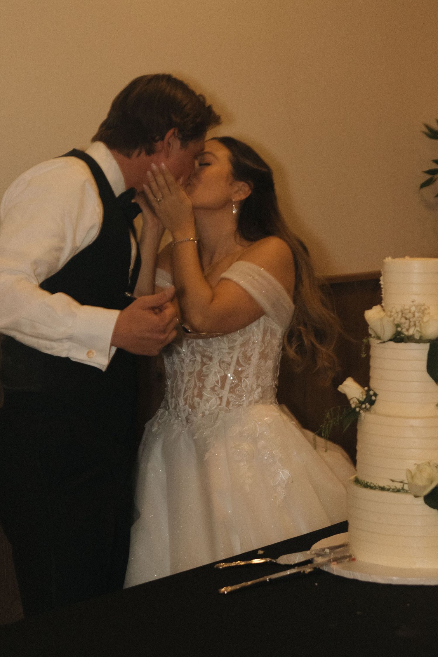 Couple sharing traditional cake cutting moment at wedding reception.