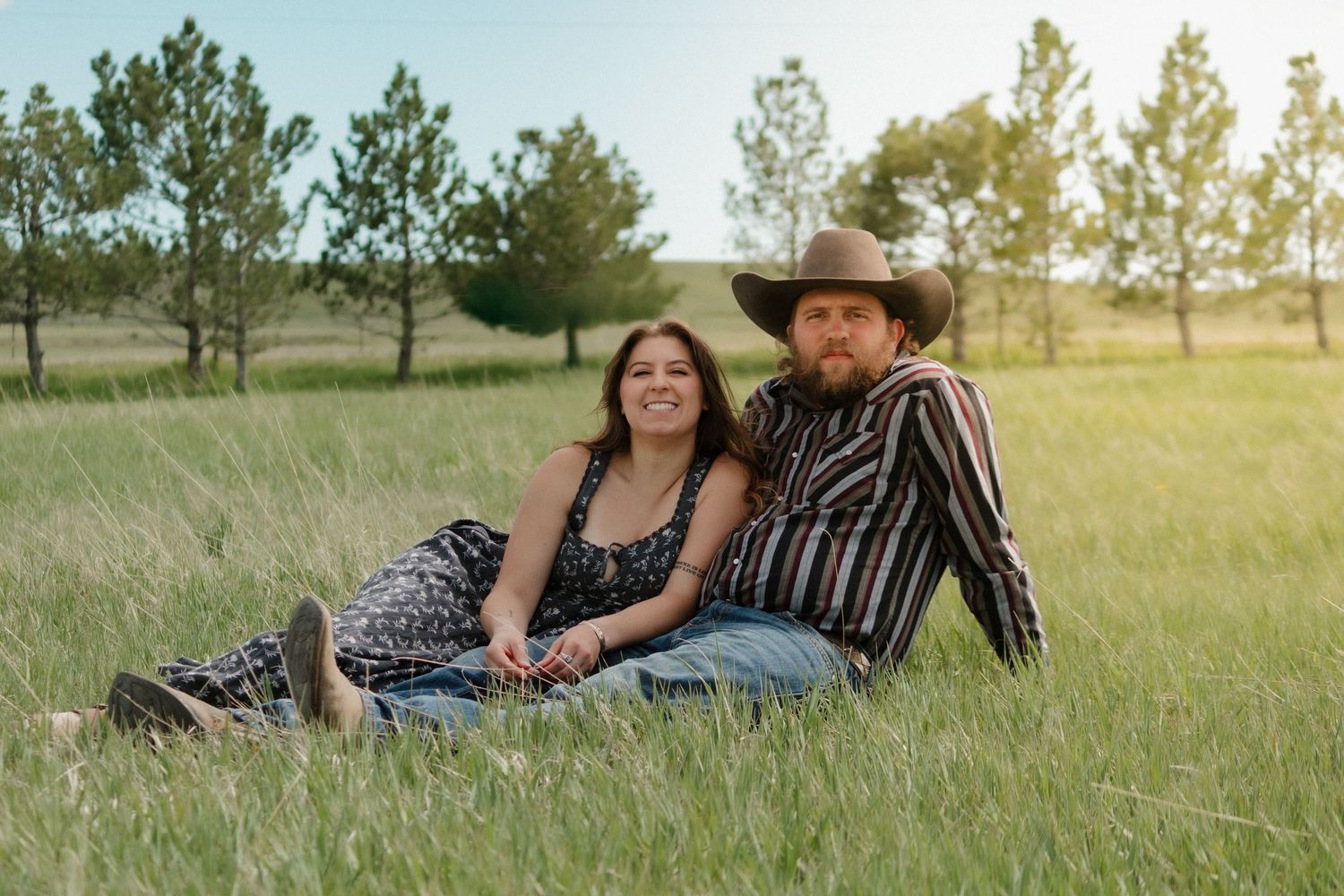 Family relaxing together in a grassy field during golden hour.