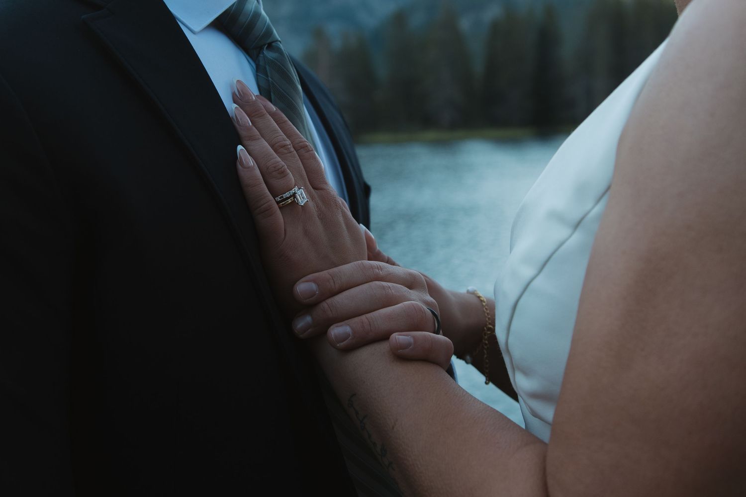 Close-up wedding photography captures intimate moments by a mountain lake.
