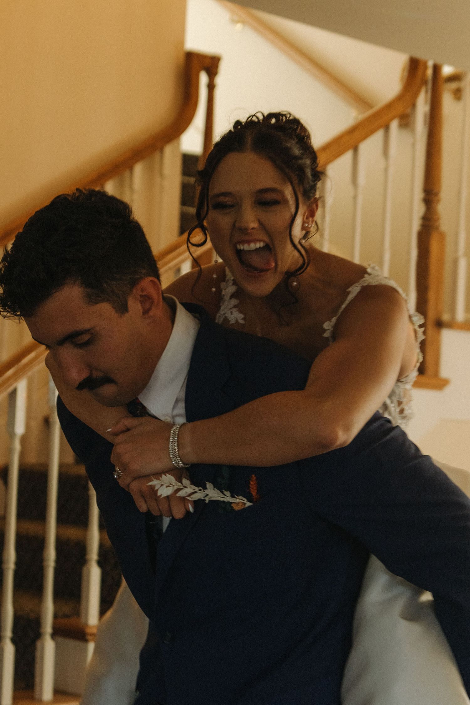 Joyful embrace captured in warm indoor lighting against a staircase.