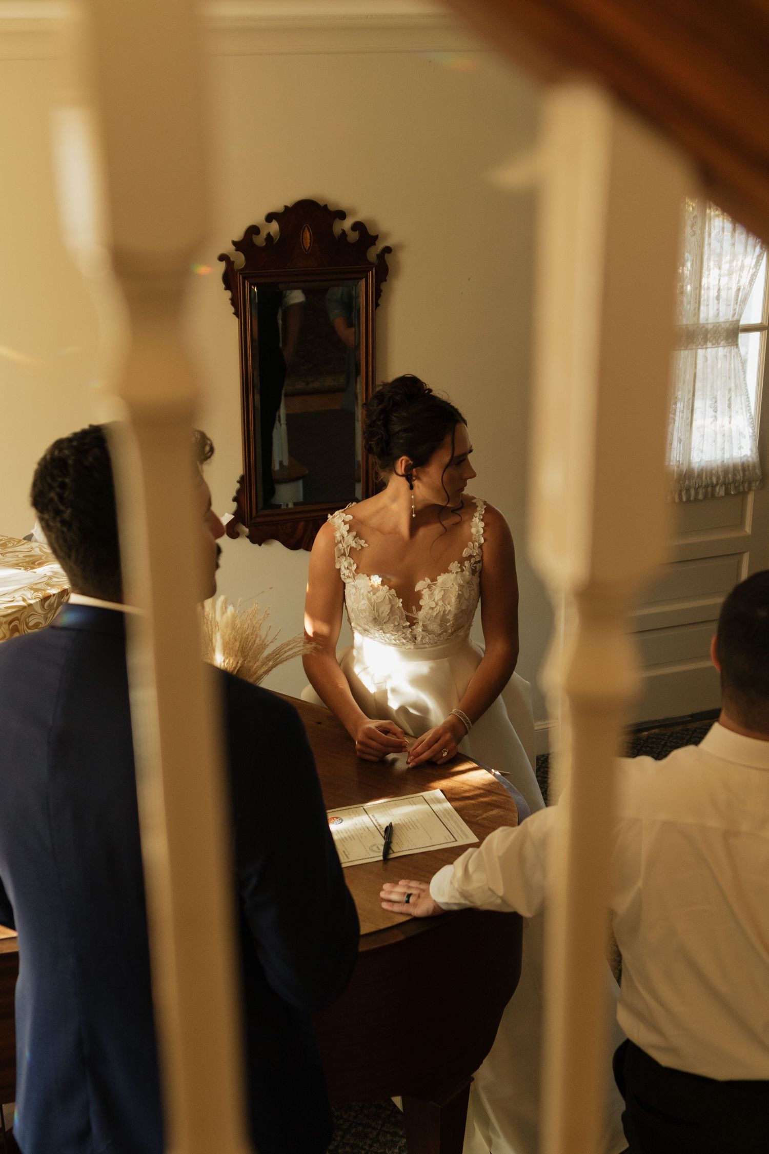 Wedding preparation moments captured through wooden railings in warm indoor lighting.