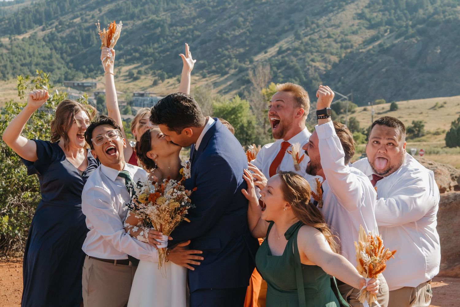 Joyful wedding celebration moment with wedding party cheering against mountain backdrop.