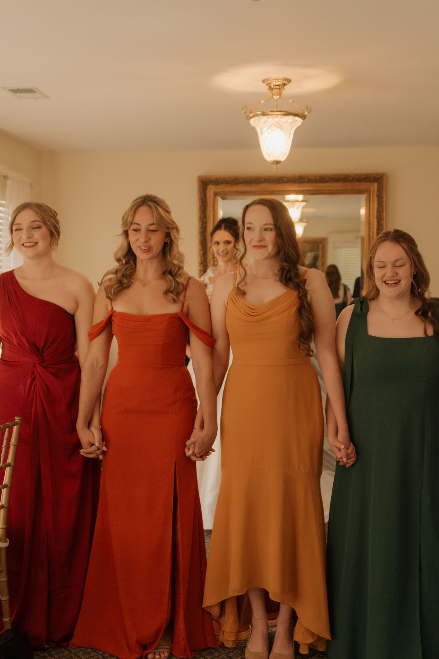 Bridesmaids wearing autumn-colored dresses in shades of red, orange and green.